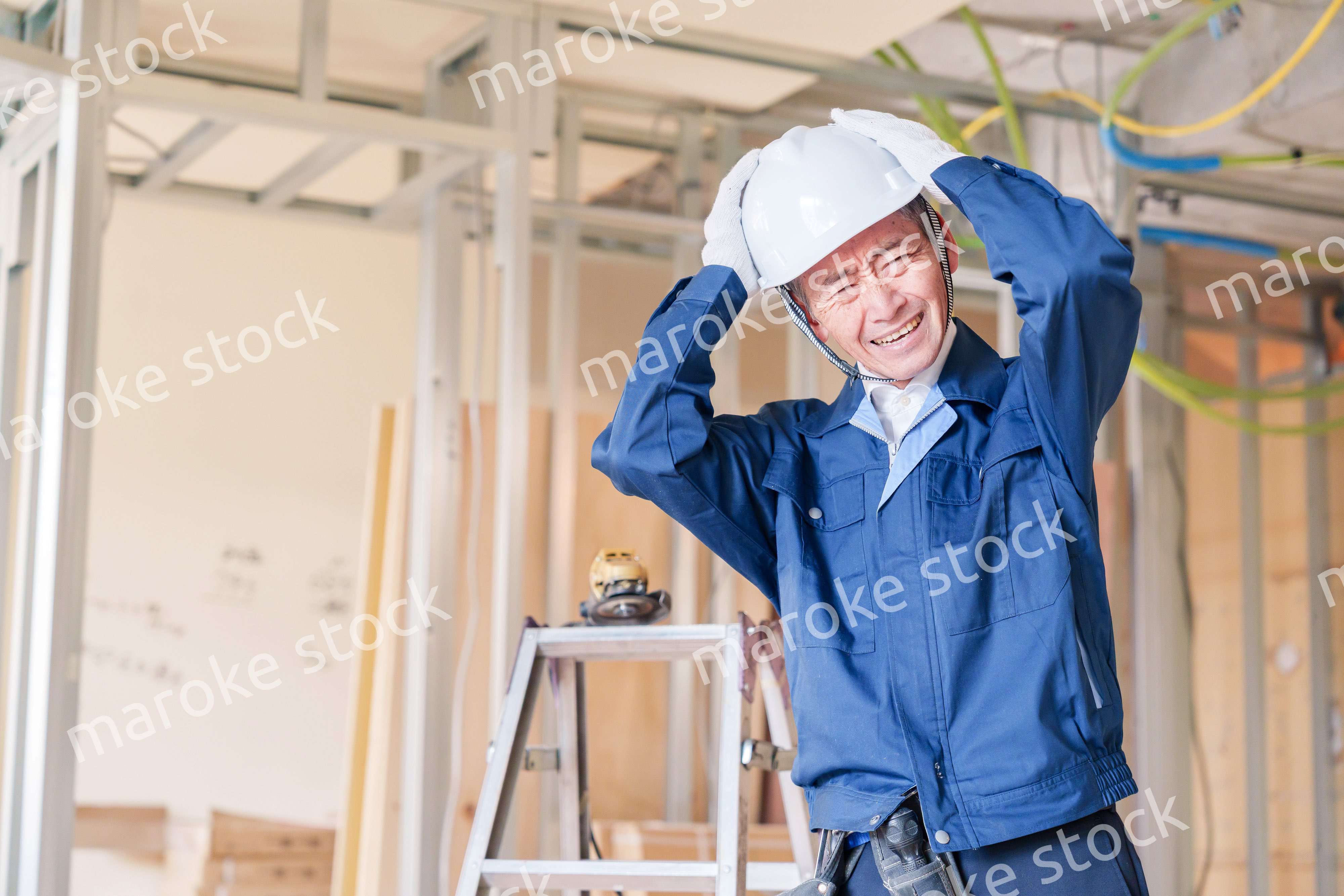 現場で頭を抱える男性の大工