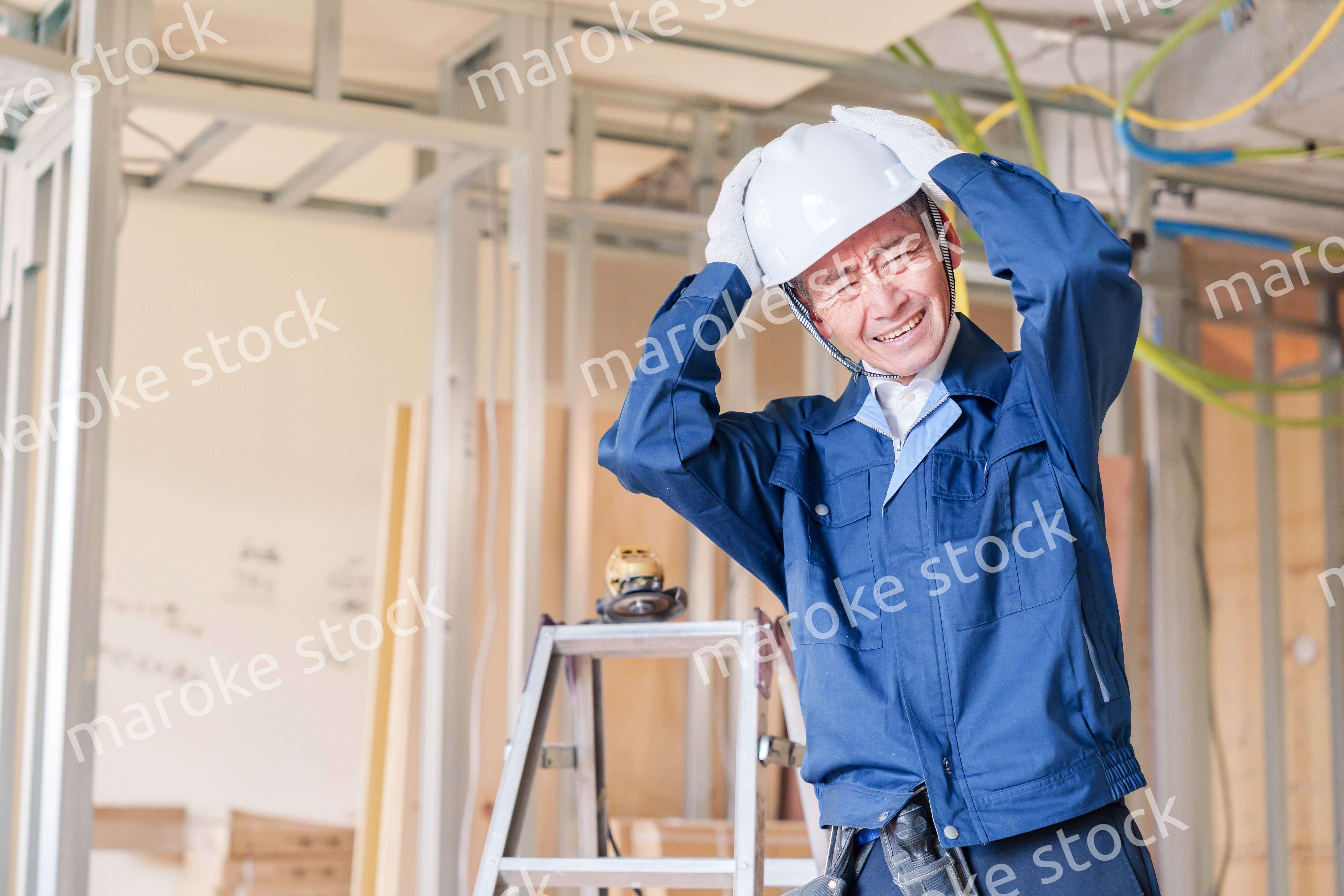 現場で頭を抱える男性の大工