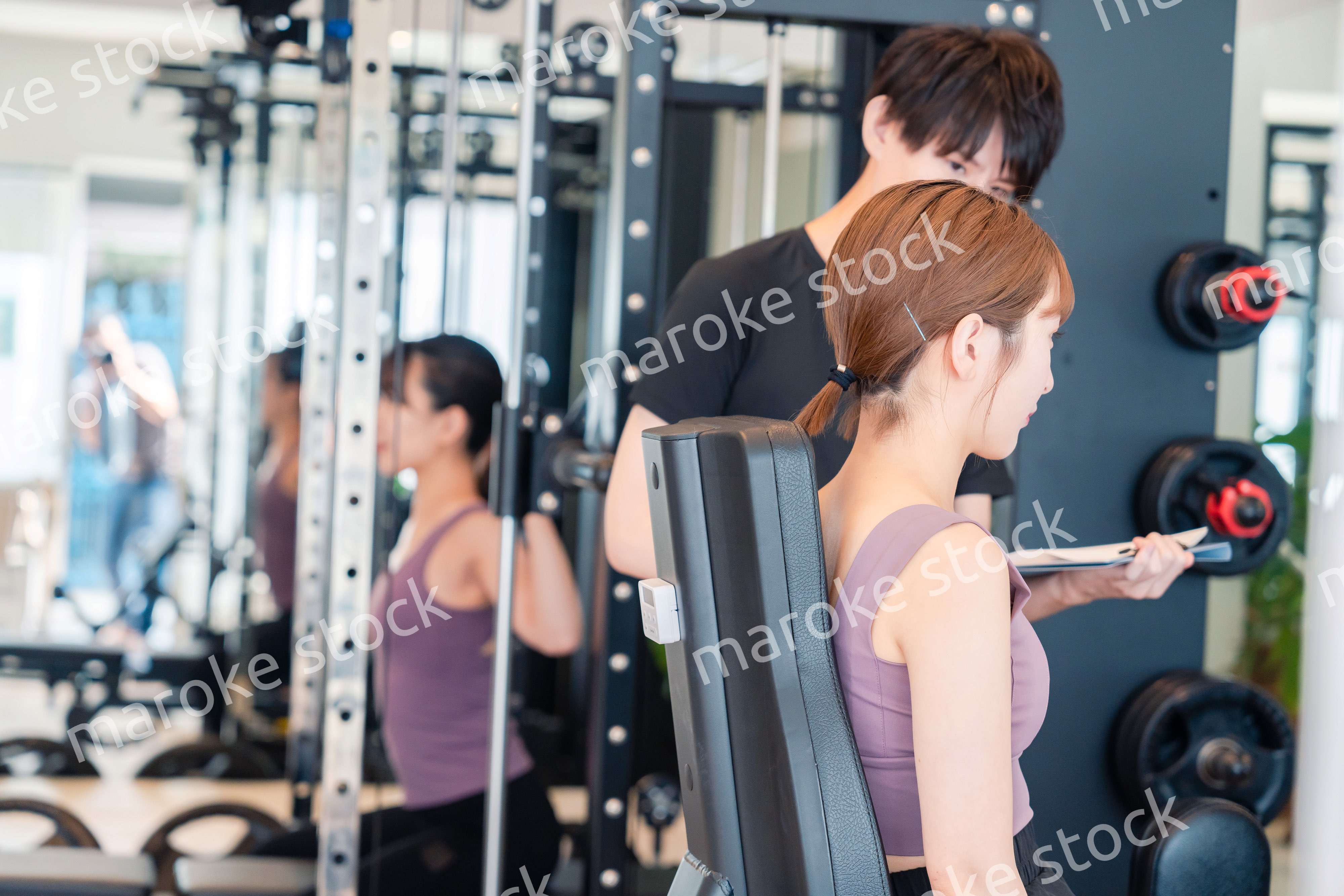 ジムのマシーンでトレーニングをする人