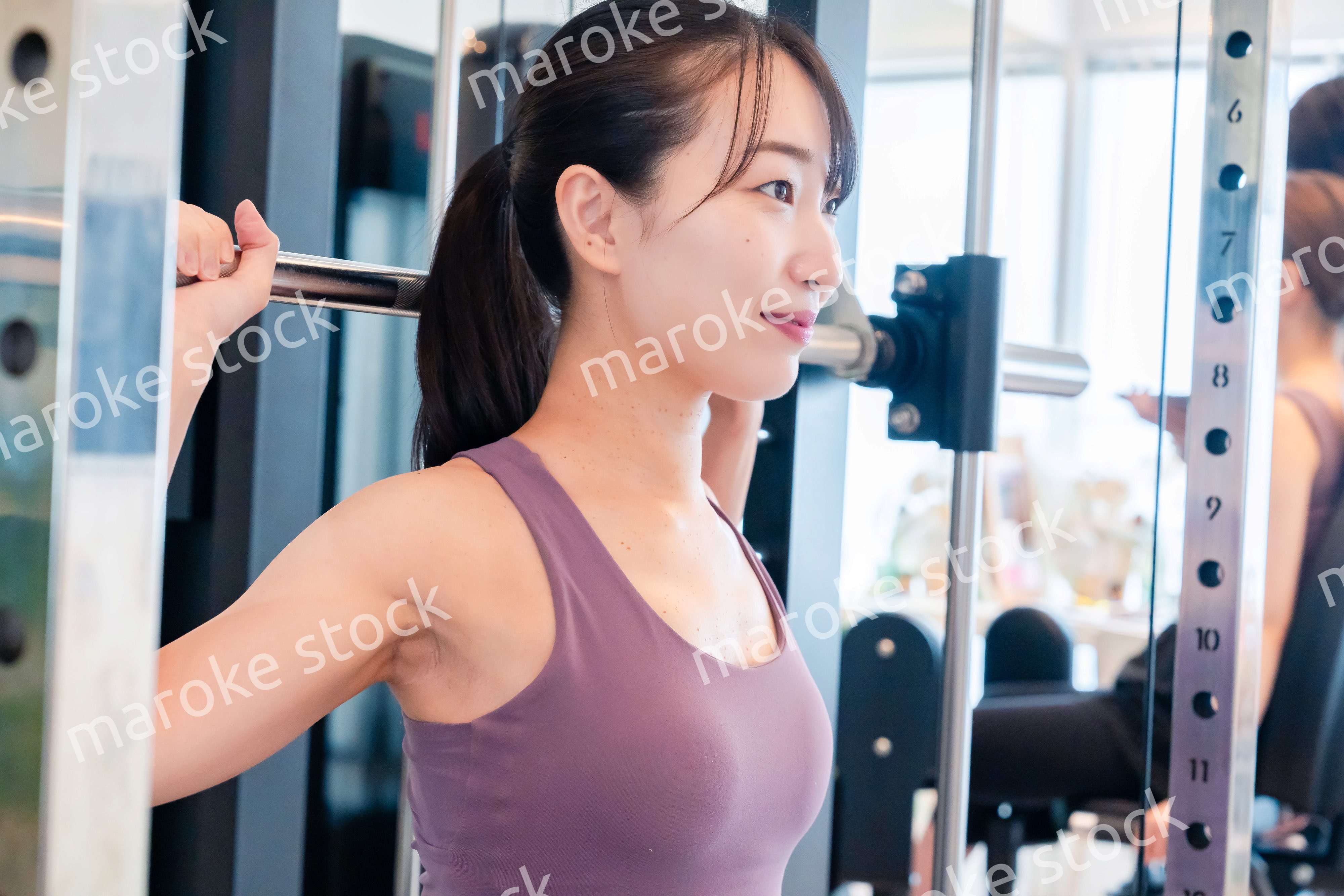 ジムのマシーンでトレーニングをする人