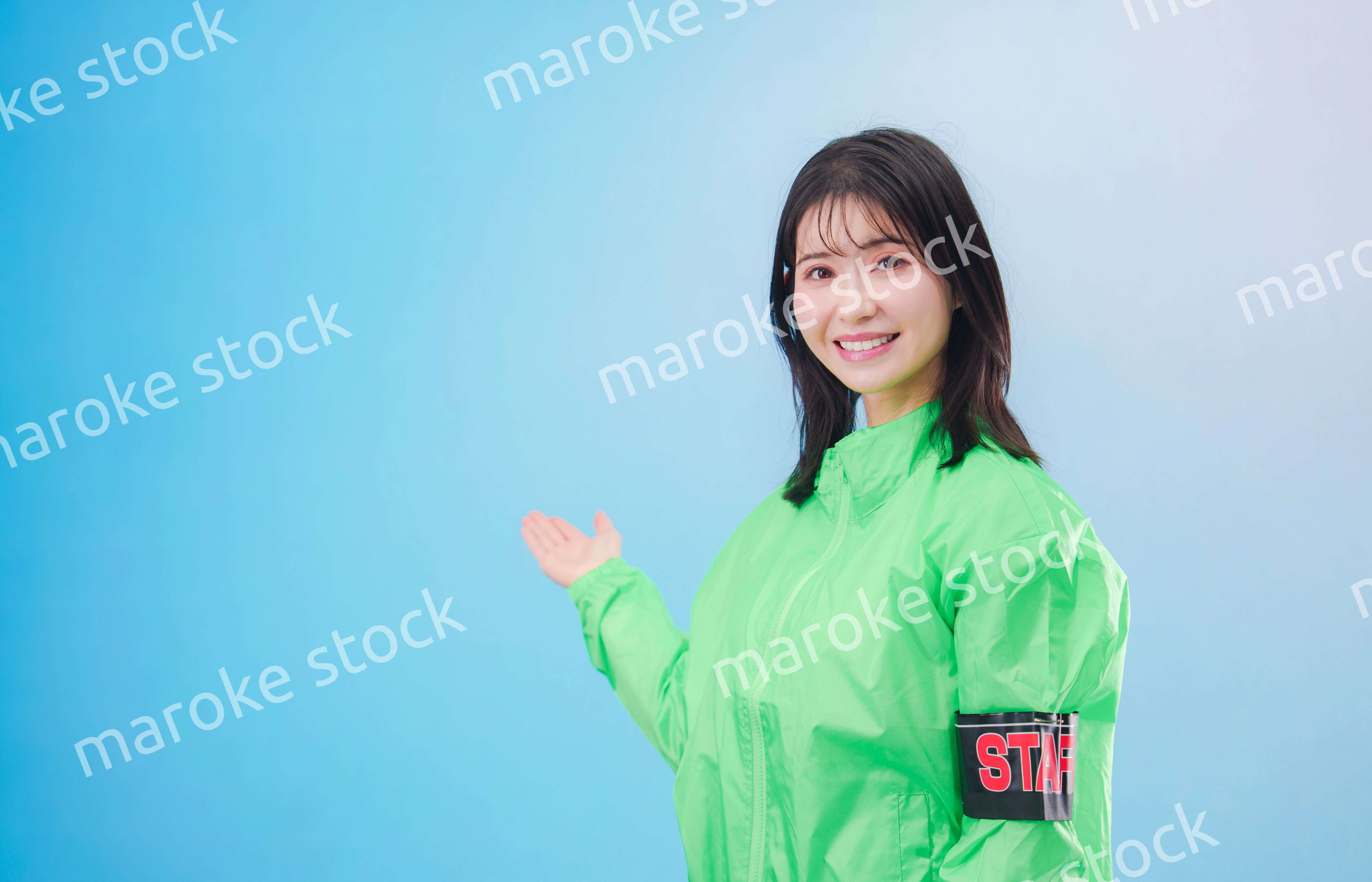 笑顔でお客様を案内するイベントスタッフ（水色背景）