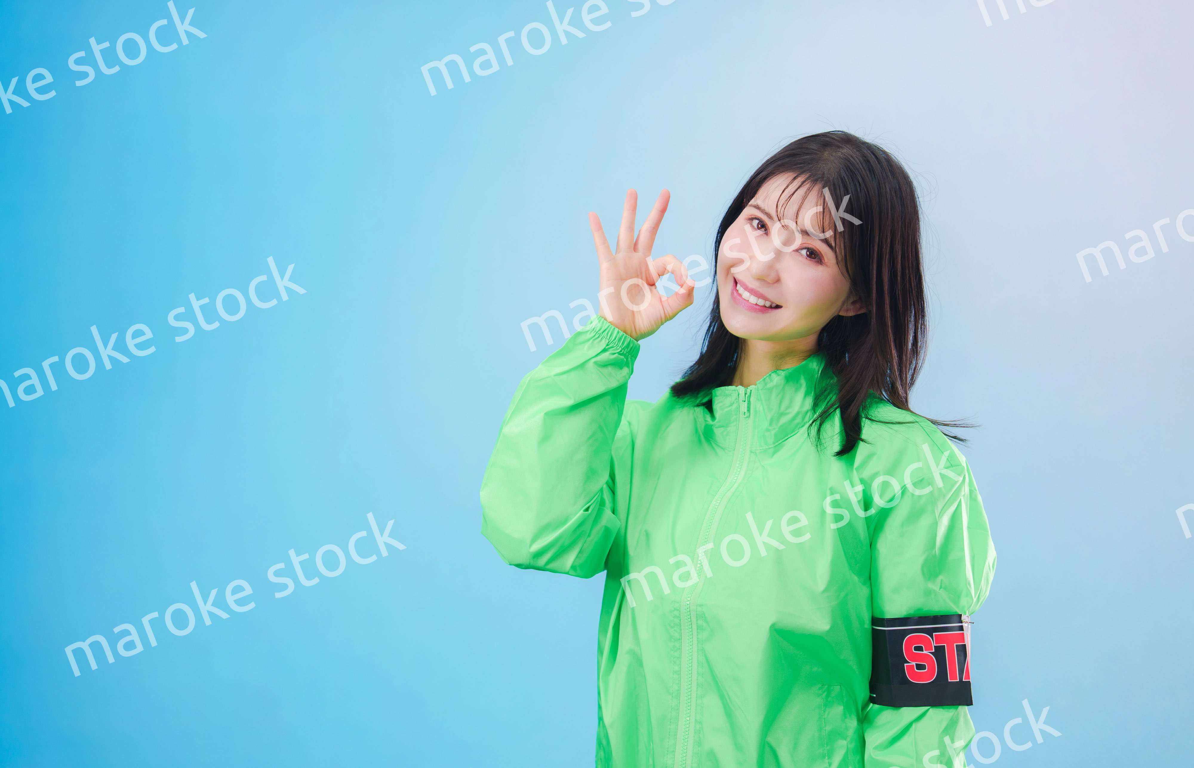 笑顔でお客様を案内するイベントスタッフ（水色背景）