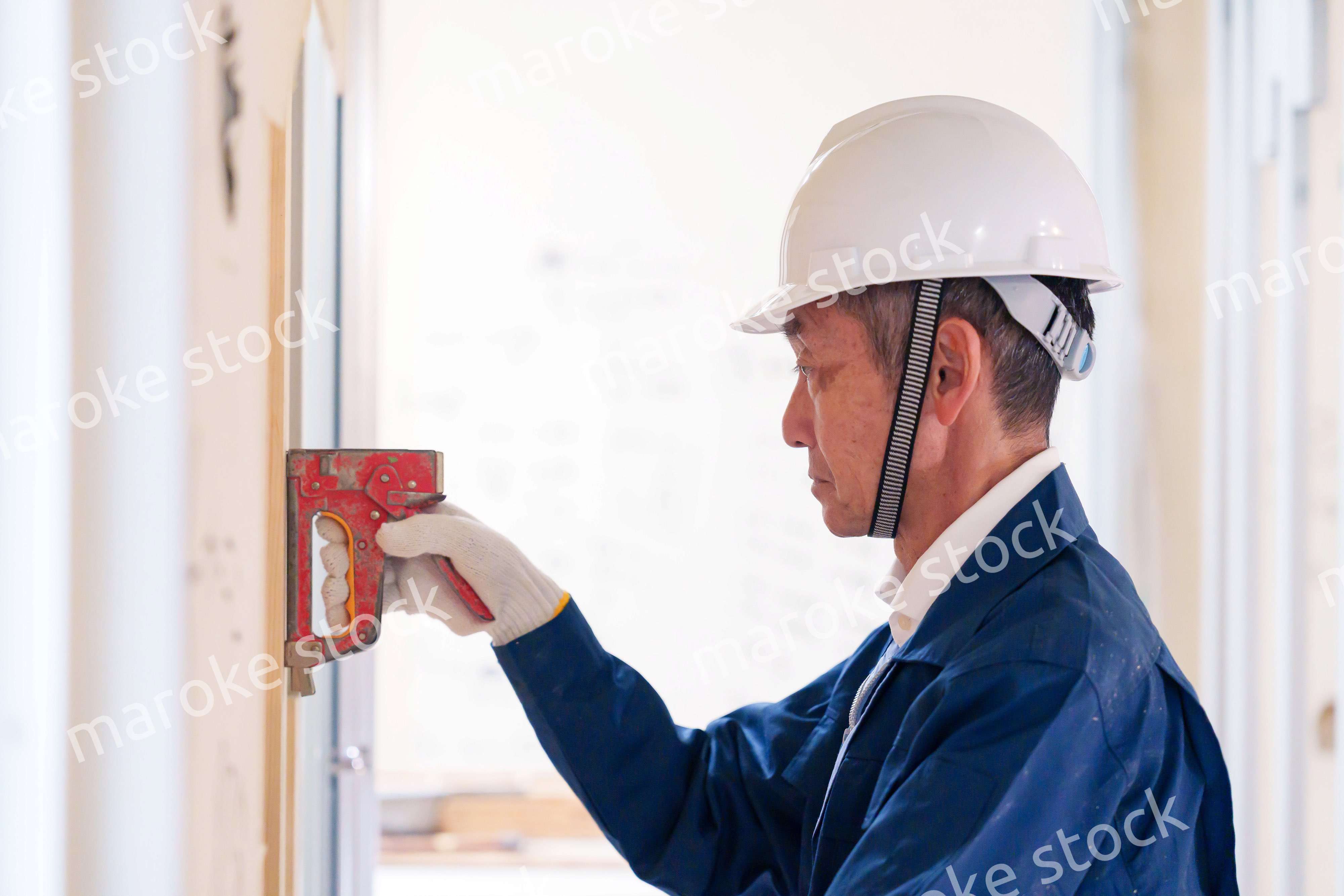 タッカーで建築資材を固定する男性の職人