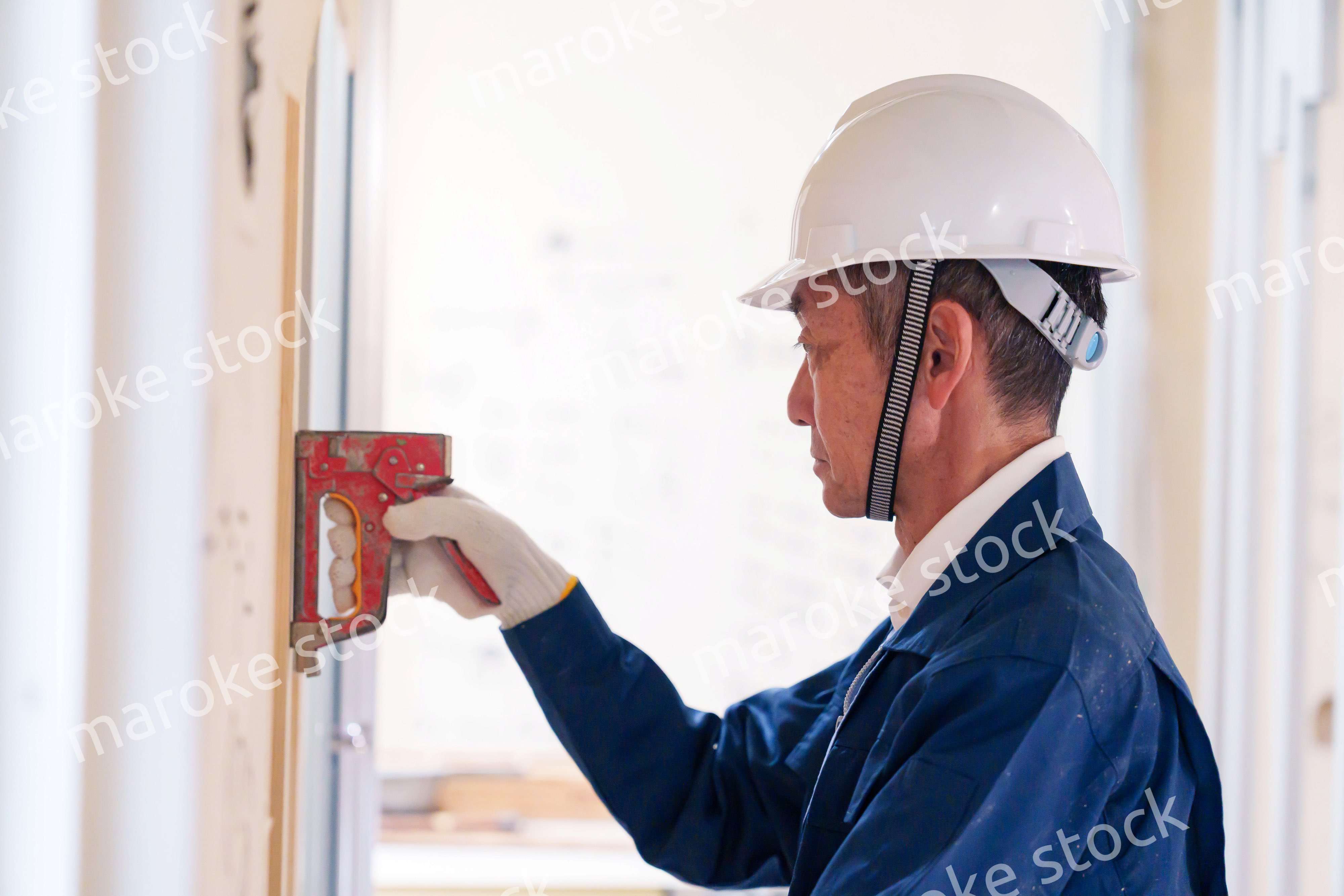 タッカーで建築資材を固定する男性の職人