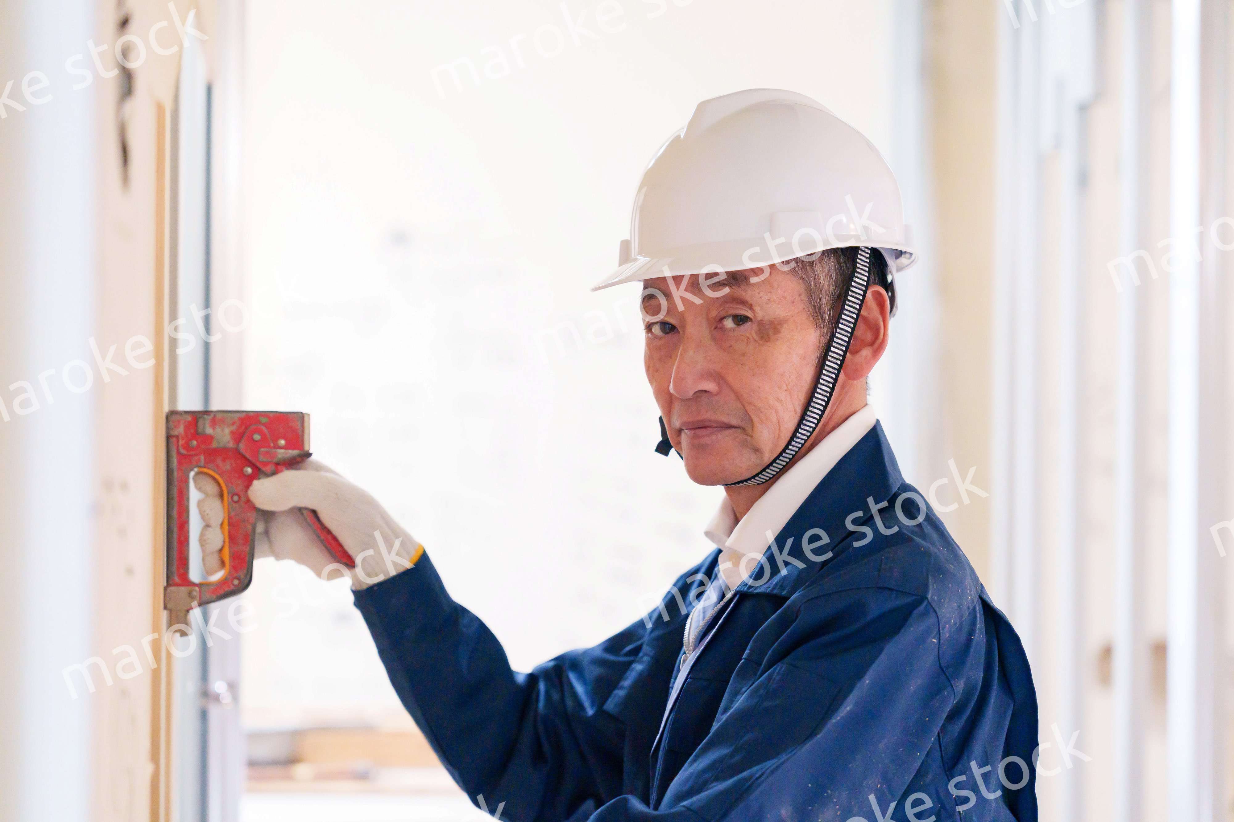 タッカーで建築資材を固定する男性の職人