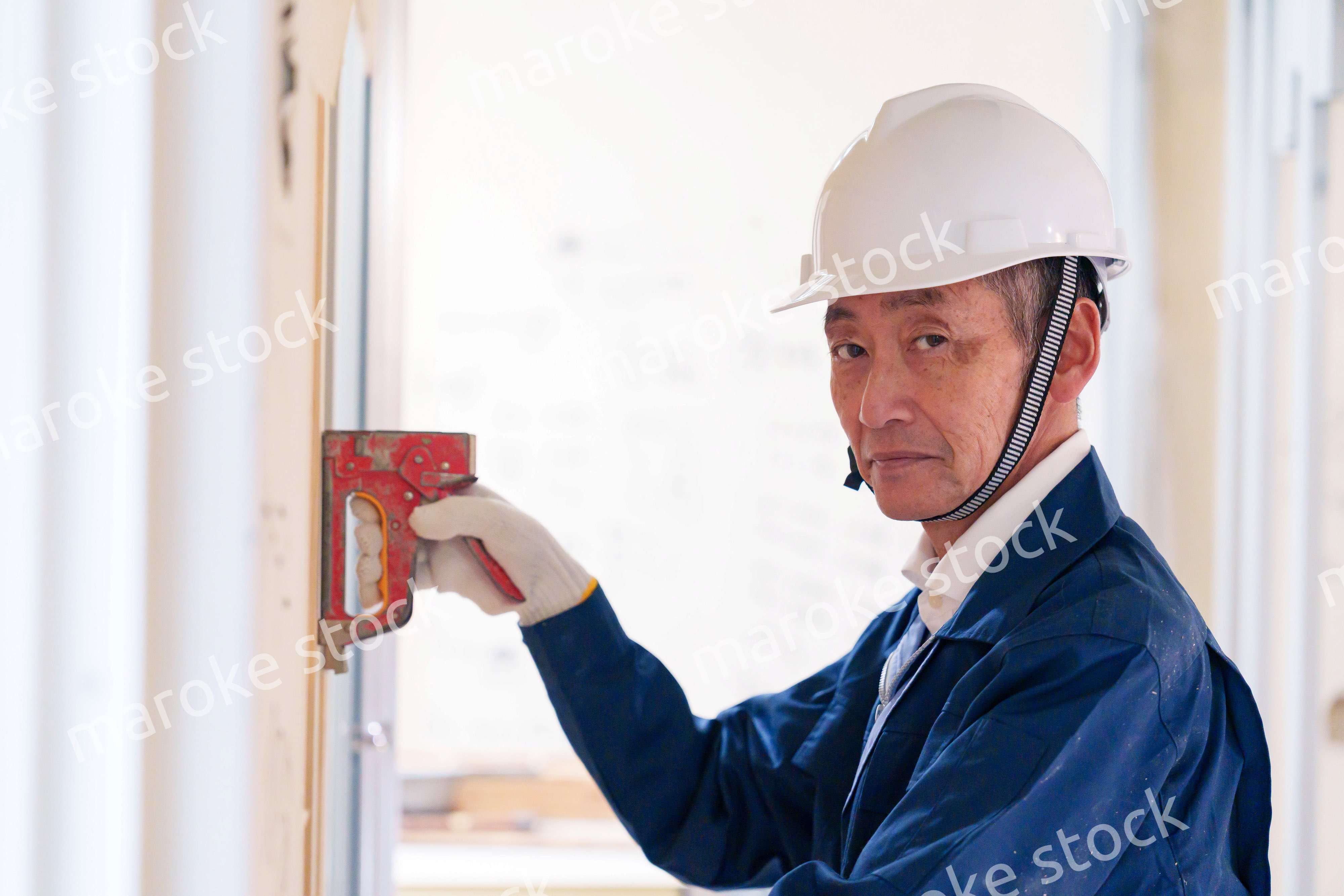 タッカーで建築資材を固定する男性の職人