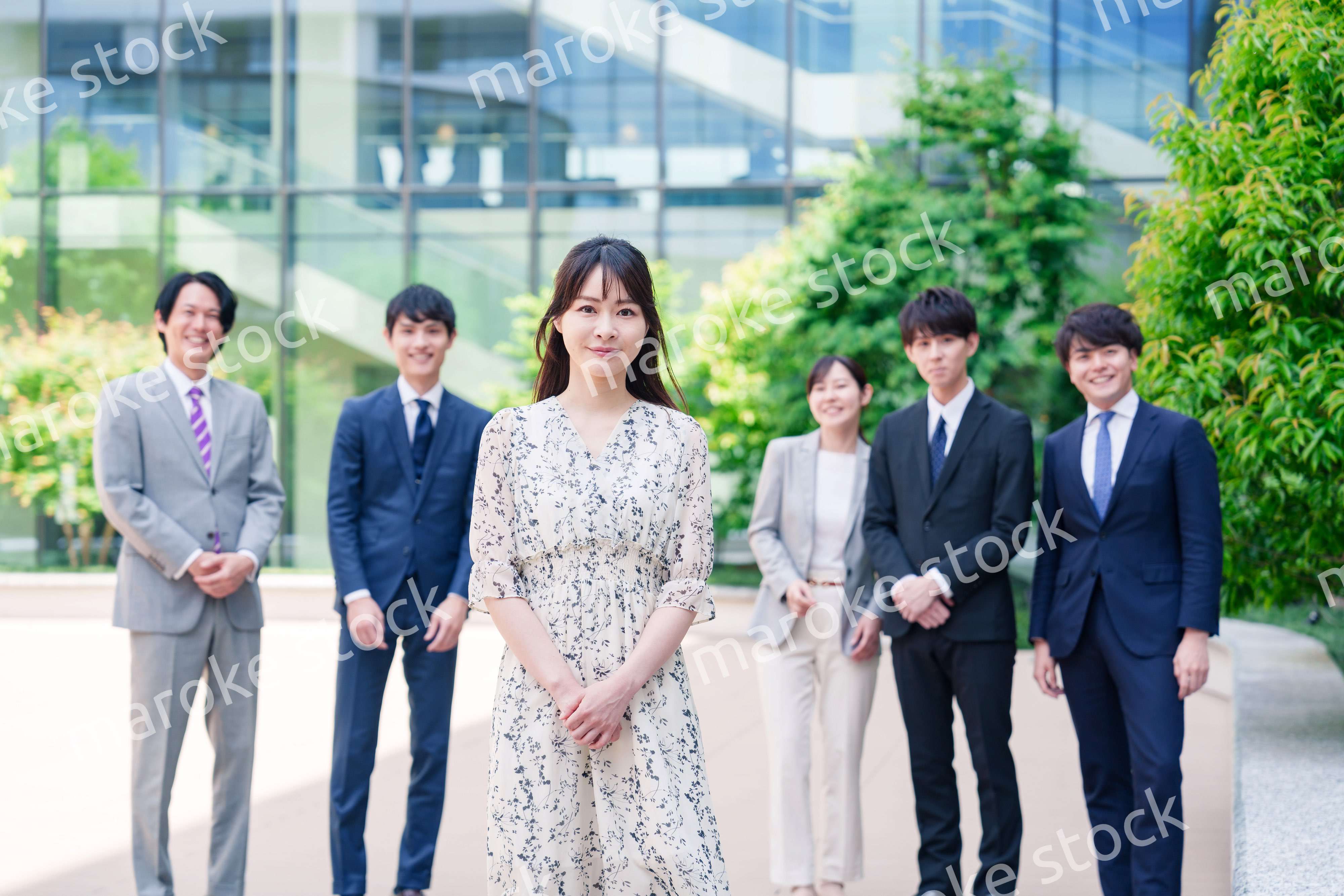 オフィス街に立つ若い女性キャリアウーマンとスタッフ