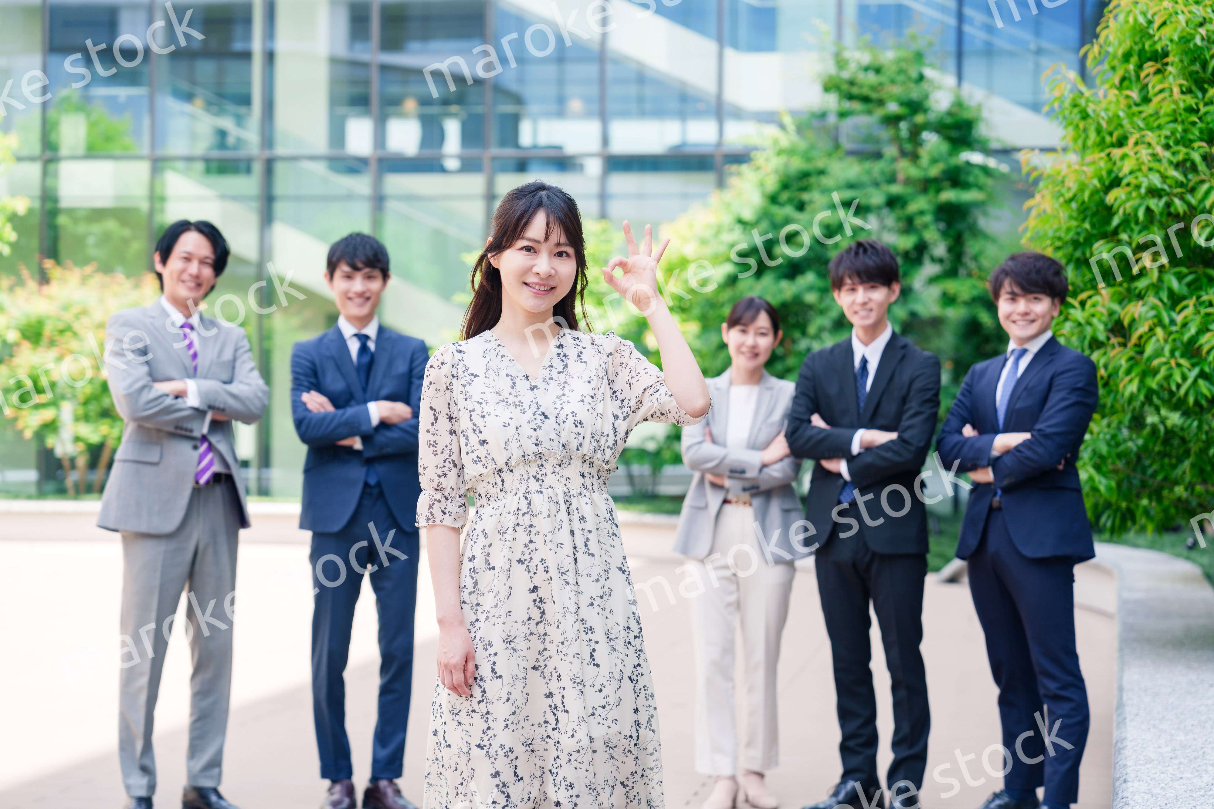 オフィス街に立つ若い女性キャリアウーマンとスタッフ