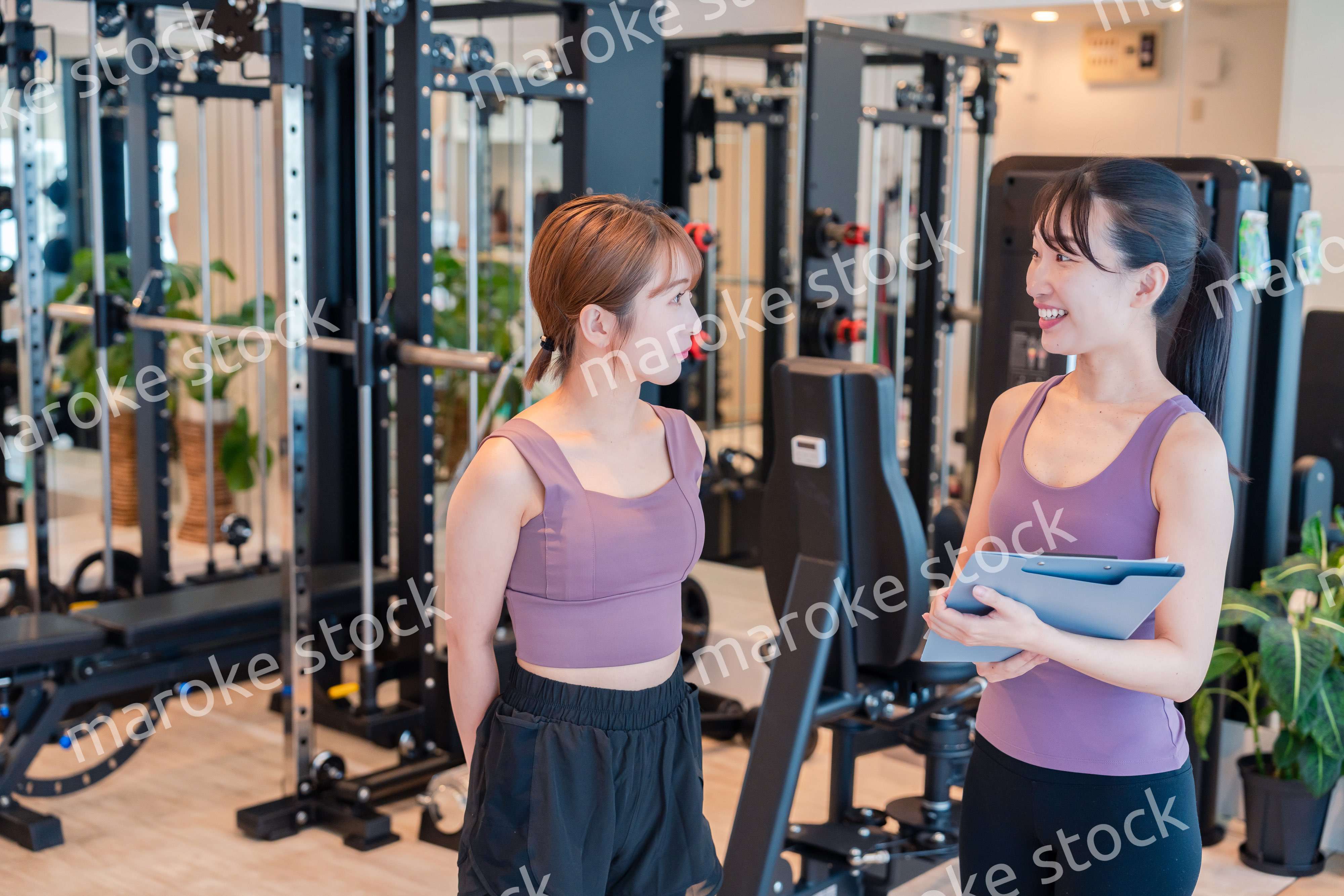 女性トレーナーからの指導を受けて筋トレをする女性