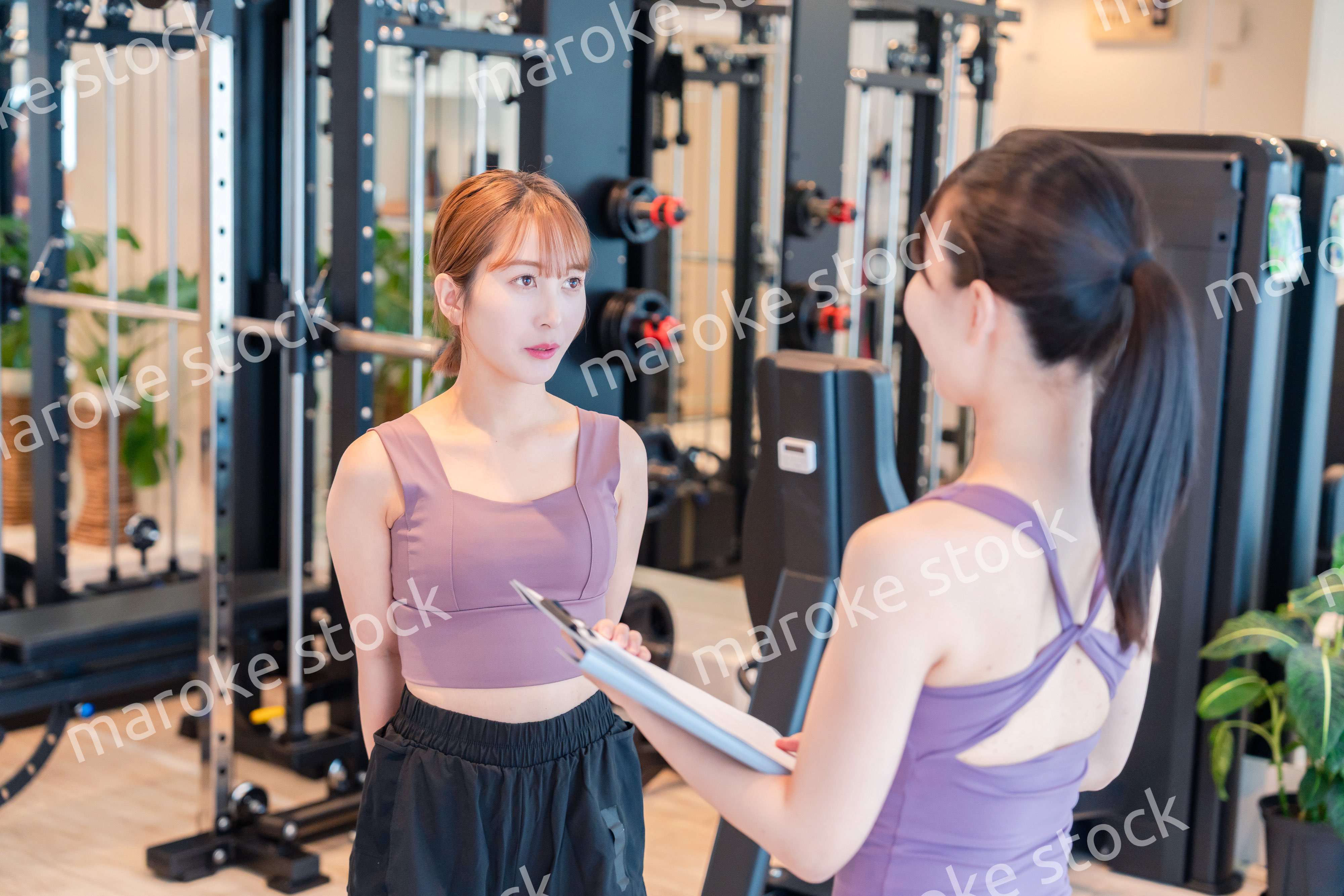 女性トレーナーからの指導を受けて筋トレをする女性