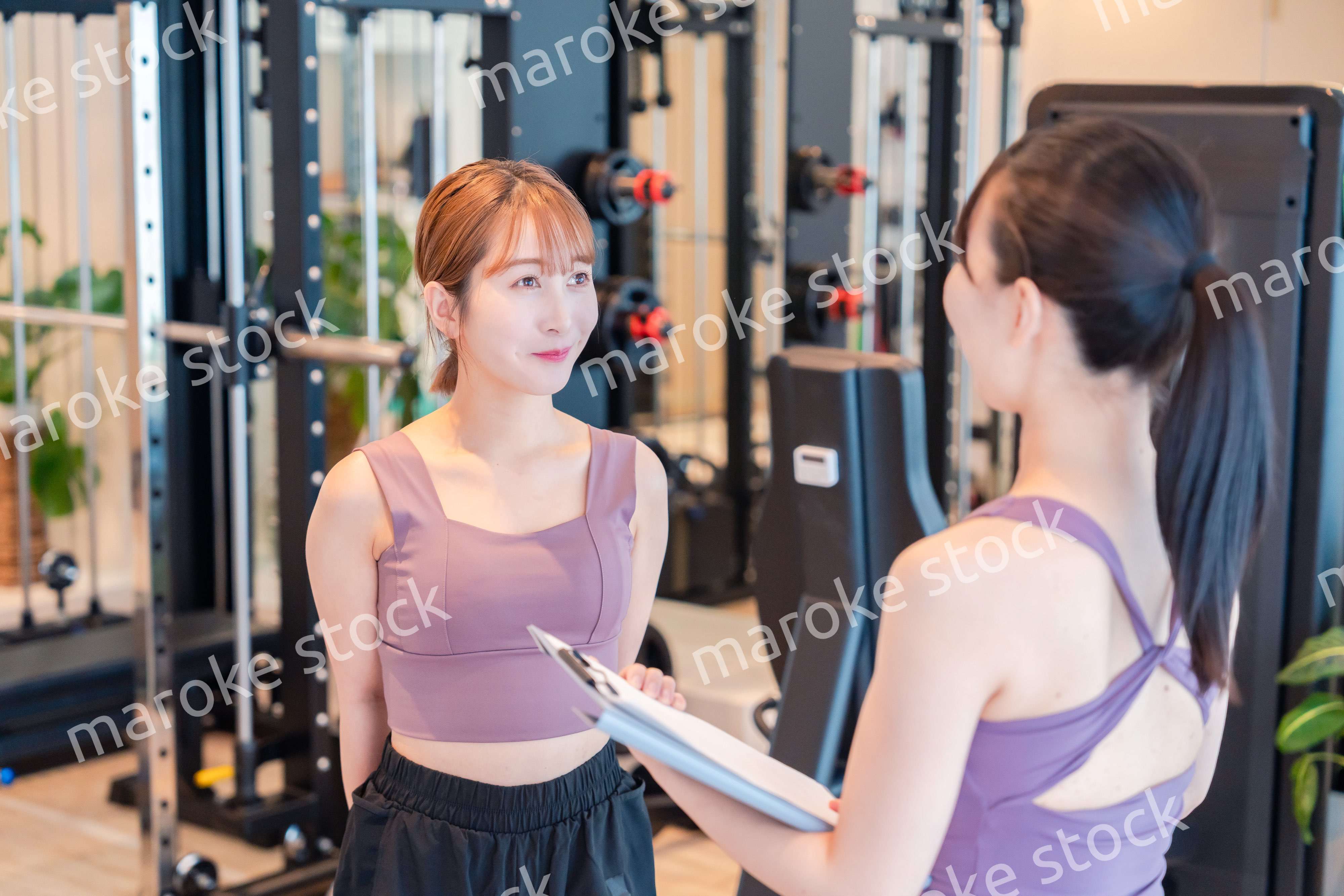 女性トレーナーからの指導を受けて筋トレをする女性