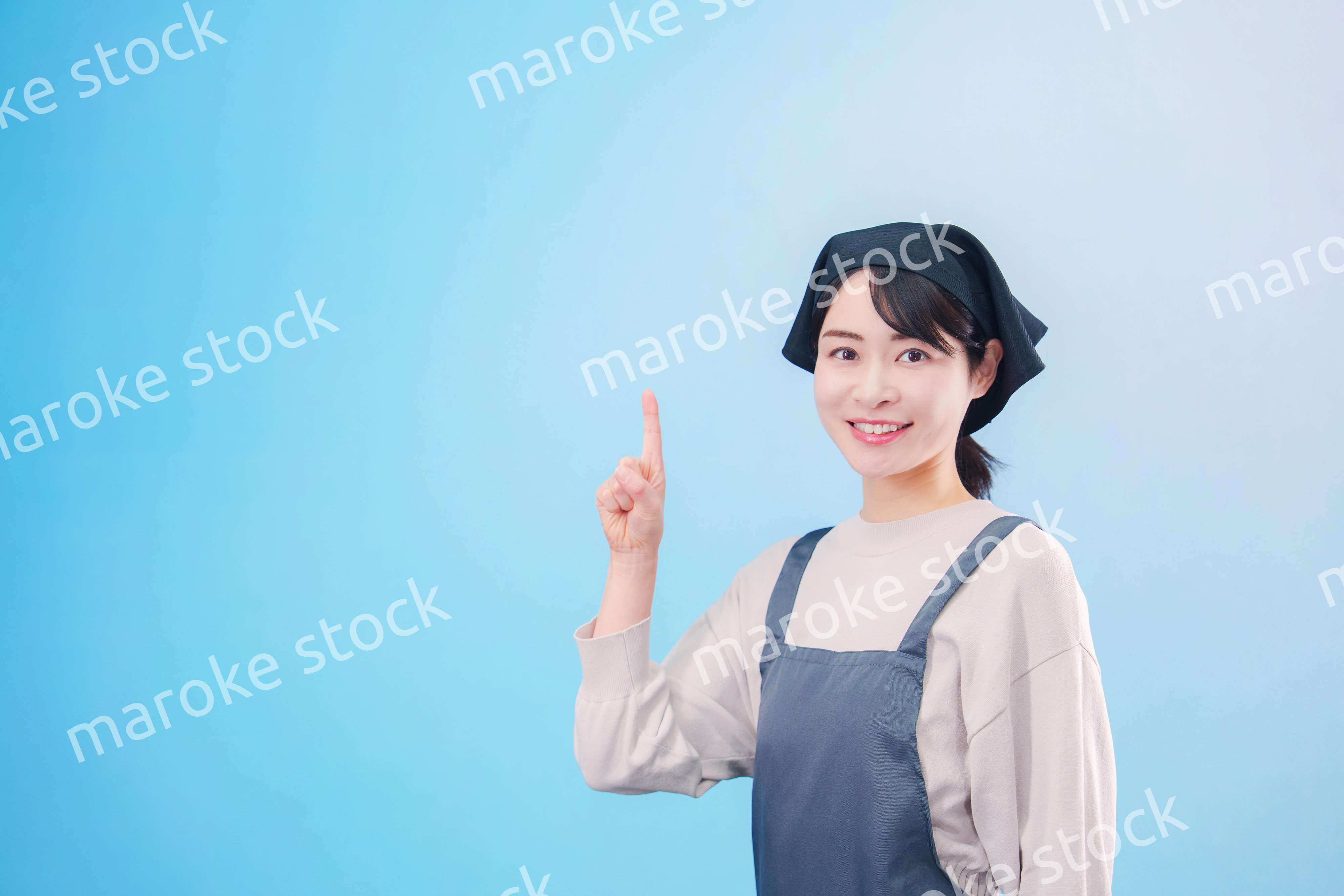エプロンを着た調理師の若い女性（水色背景）