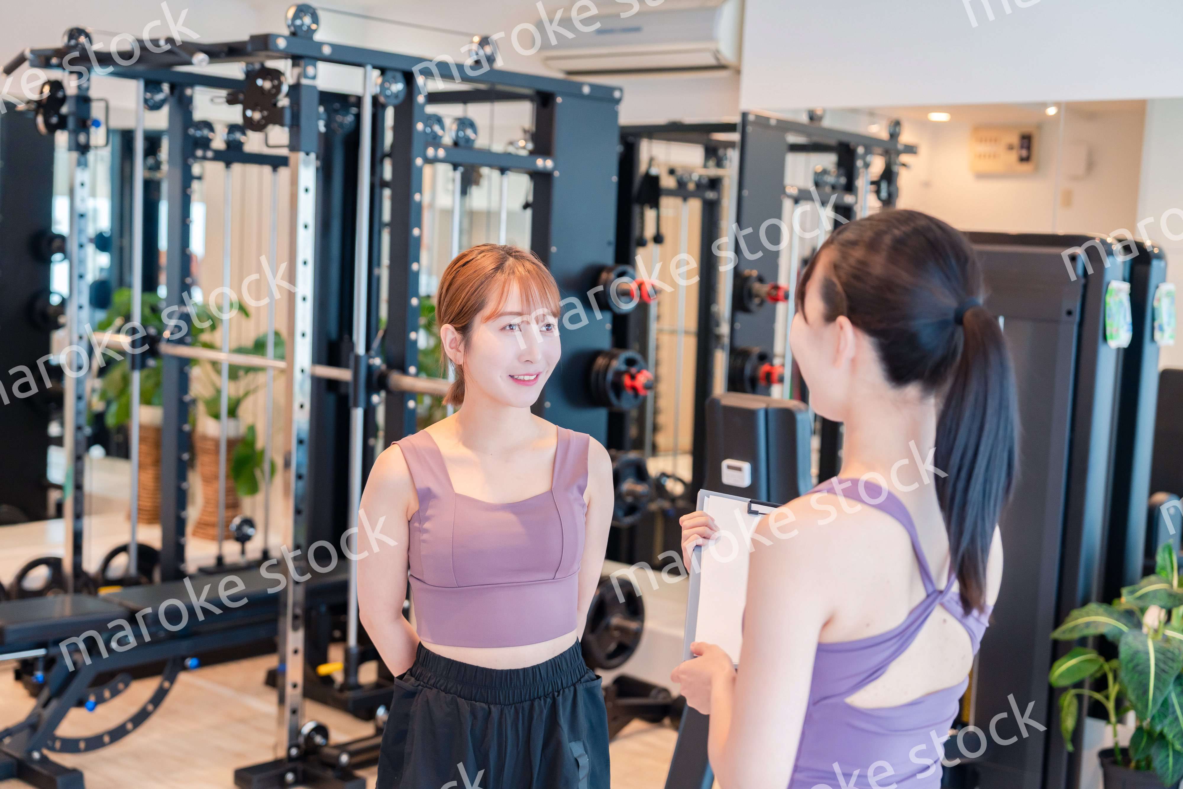 女性トレーナーからの指導を受けて筋トレをする女性