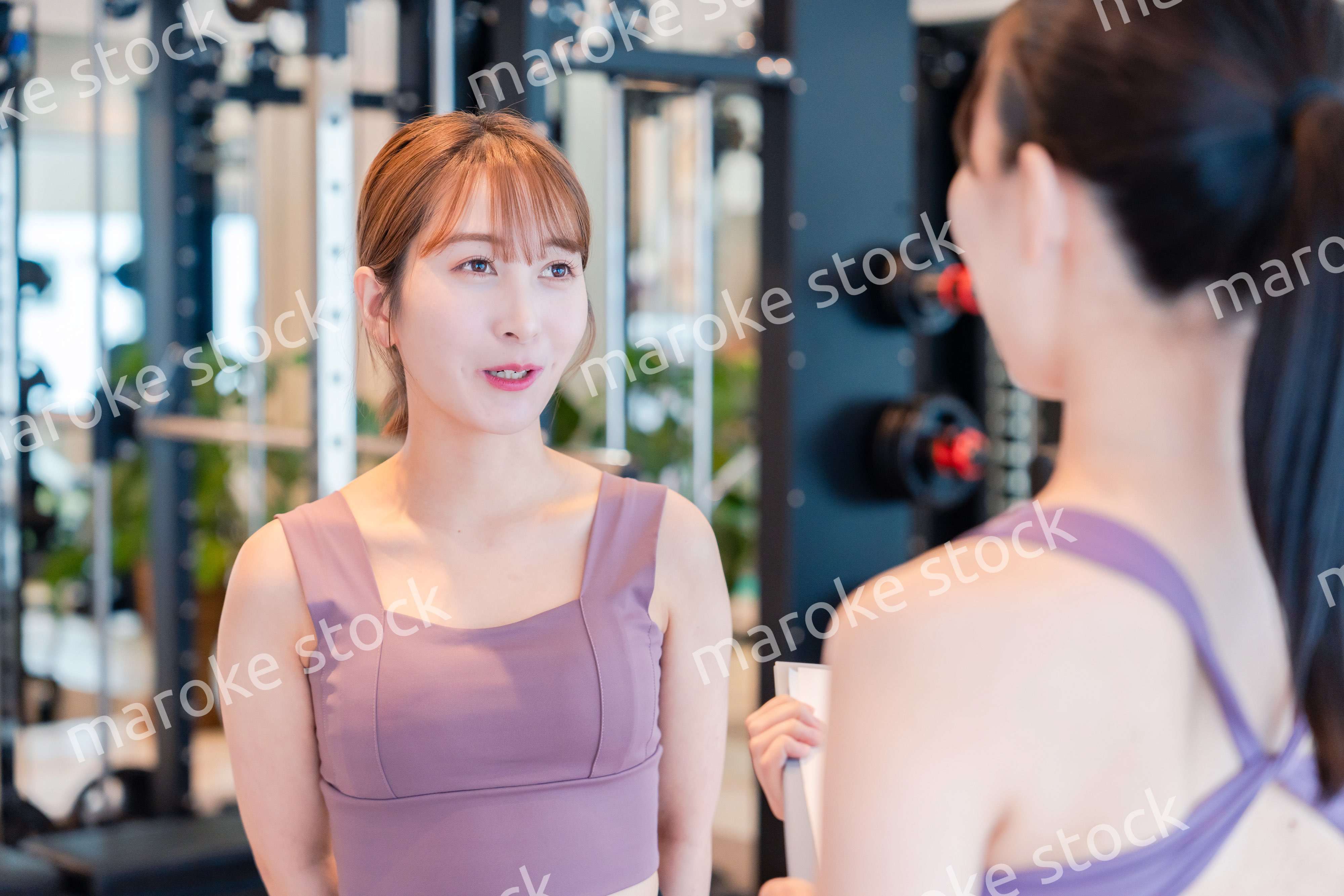 女性トレーナーからの指導を受けて筋トレをする女性