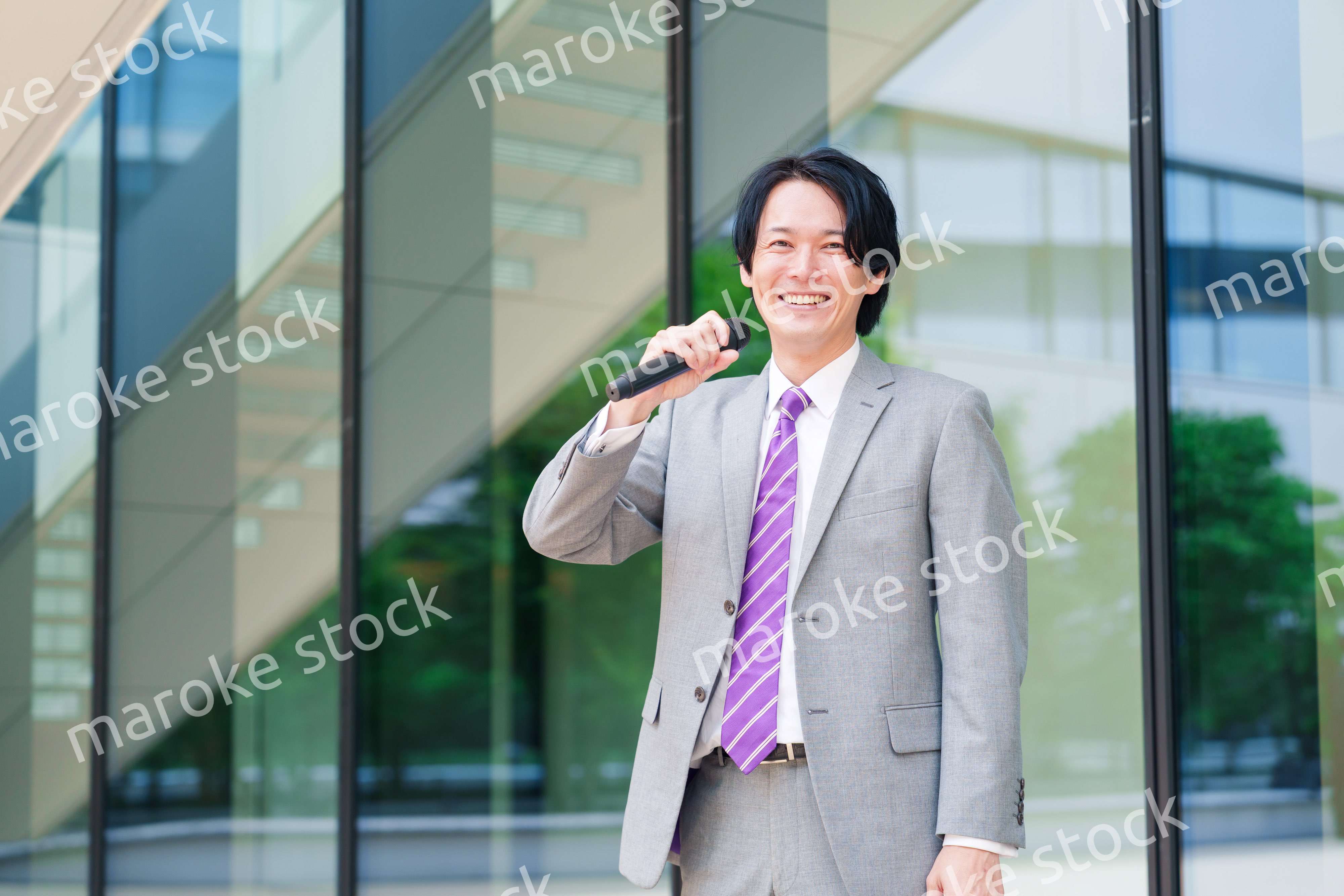マイクを使って街なかで演説をするスーツを着た男性