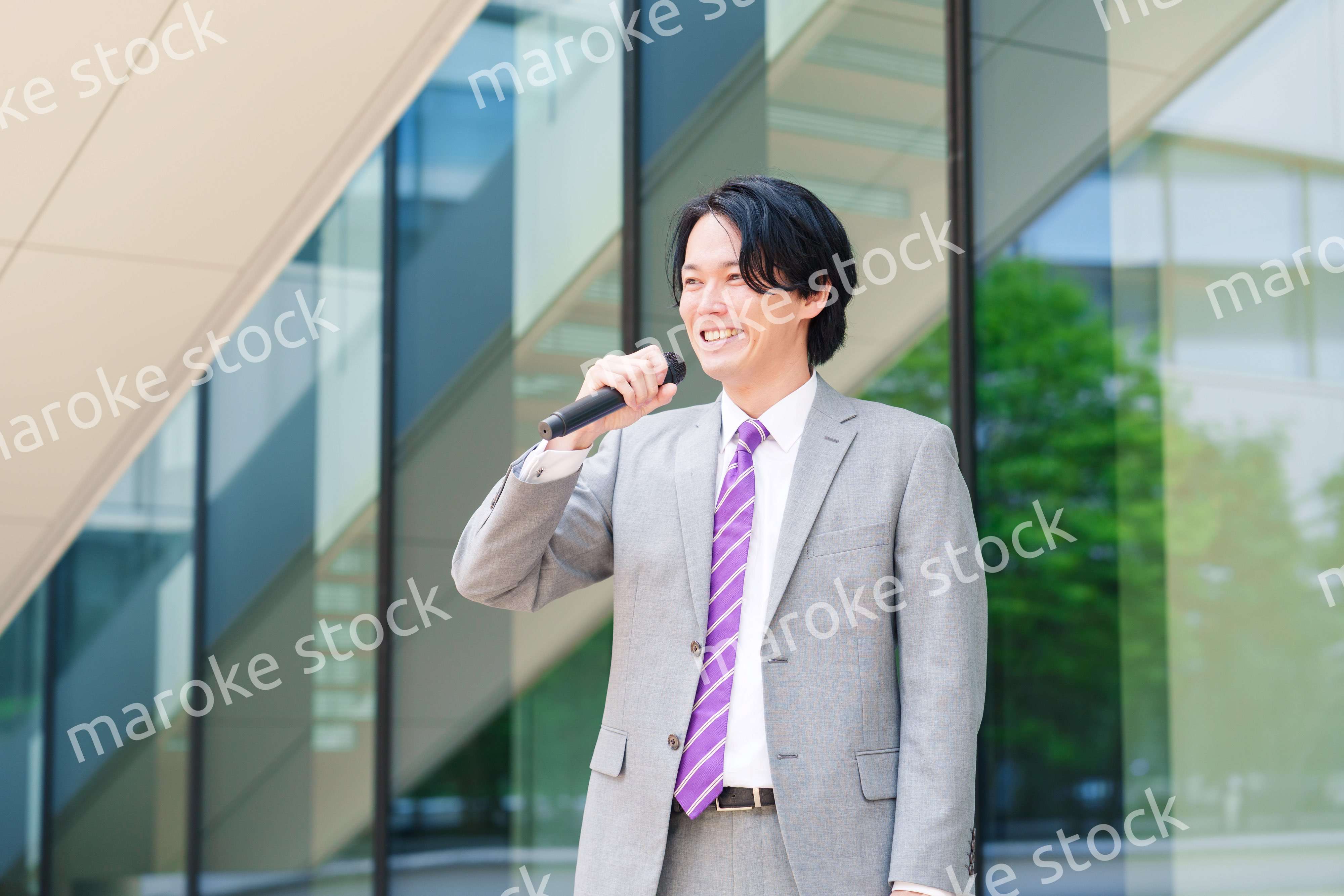 マイクを使って街なかで演説をするスーツを着た男性