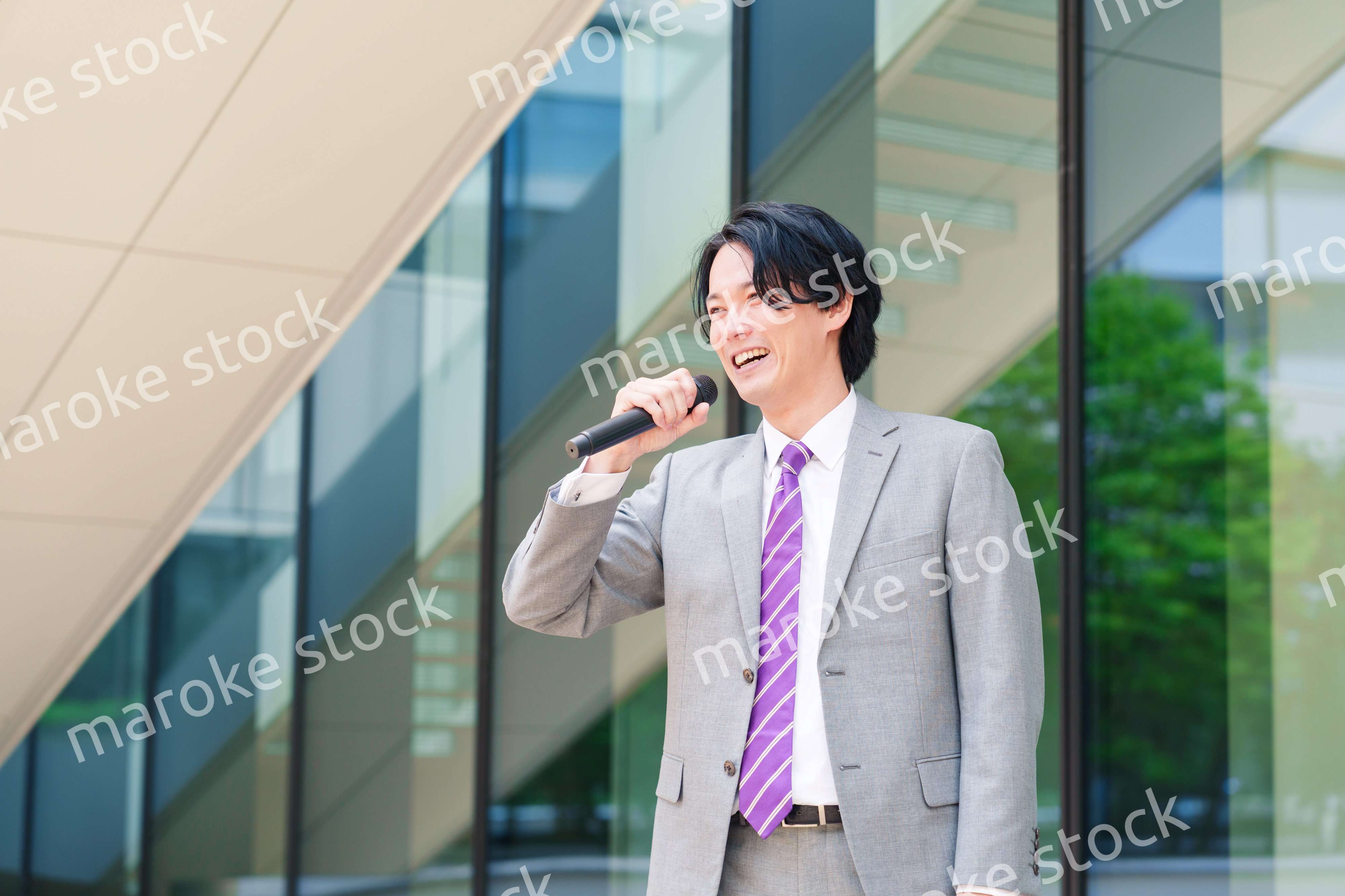 マイクを使って街なかで演説をするスーツを着た男性