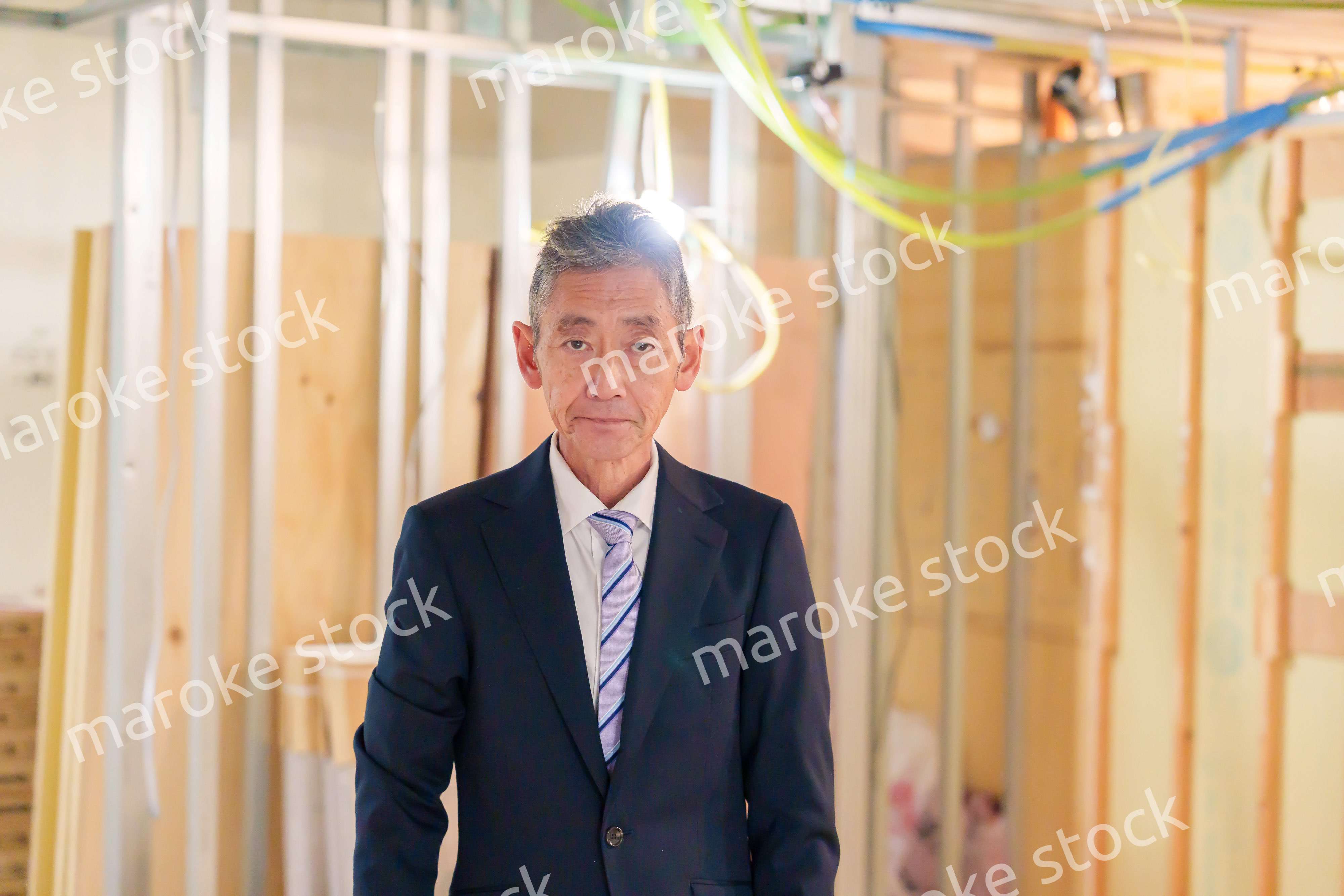 スーツ姿で現場に立つ工務店の男性経営者