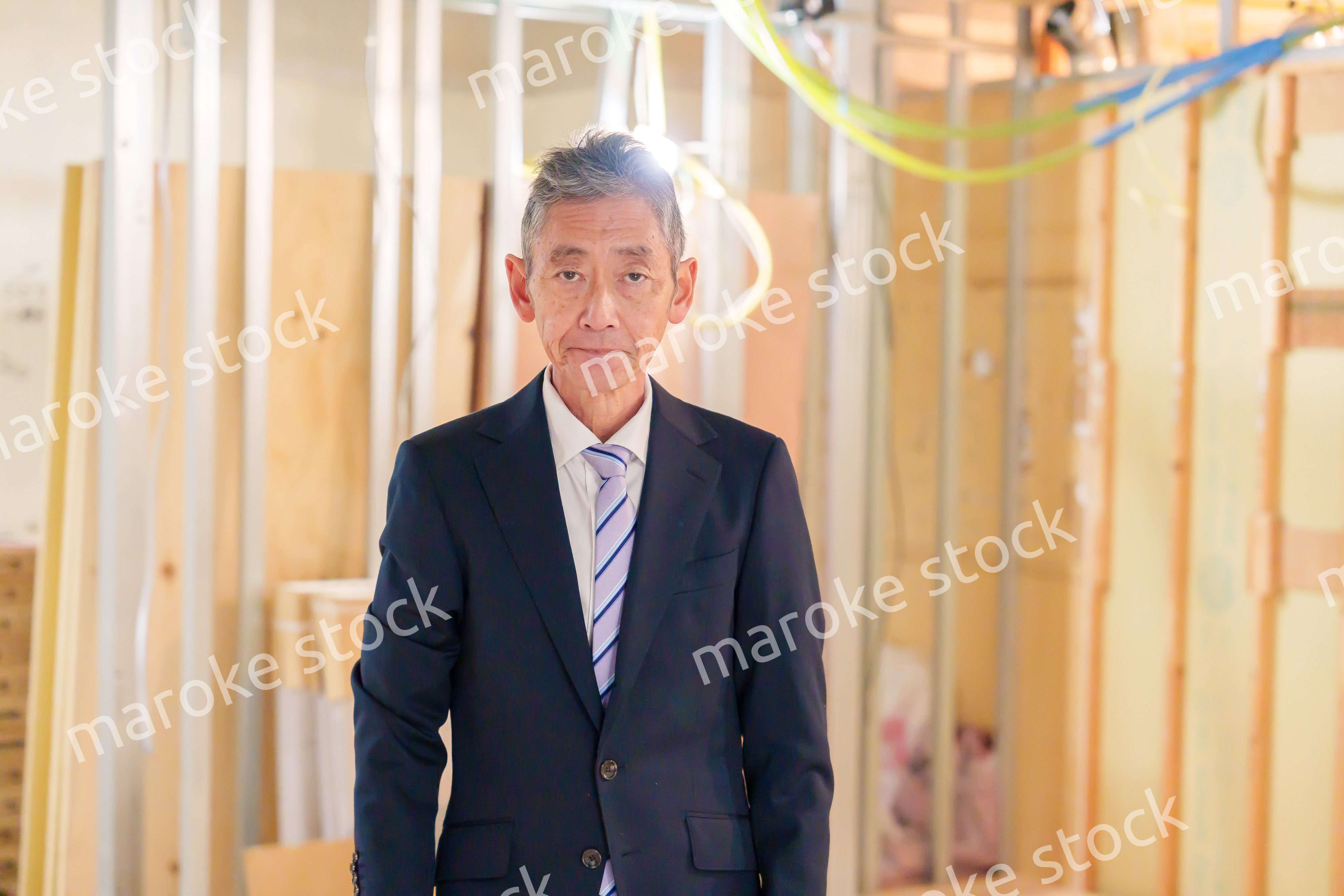 スーツ姿で現場に立つ工務店の男性経営者