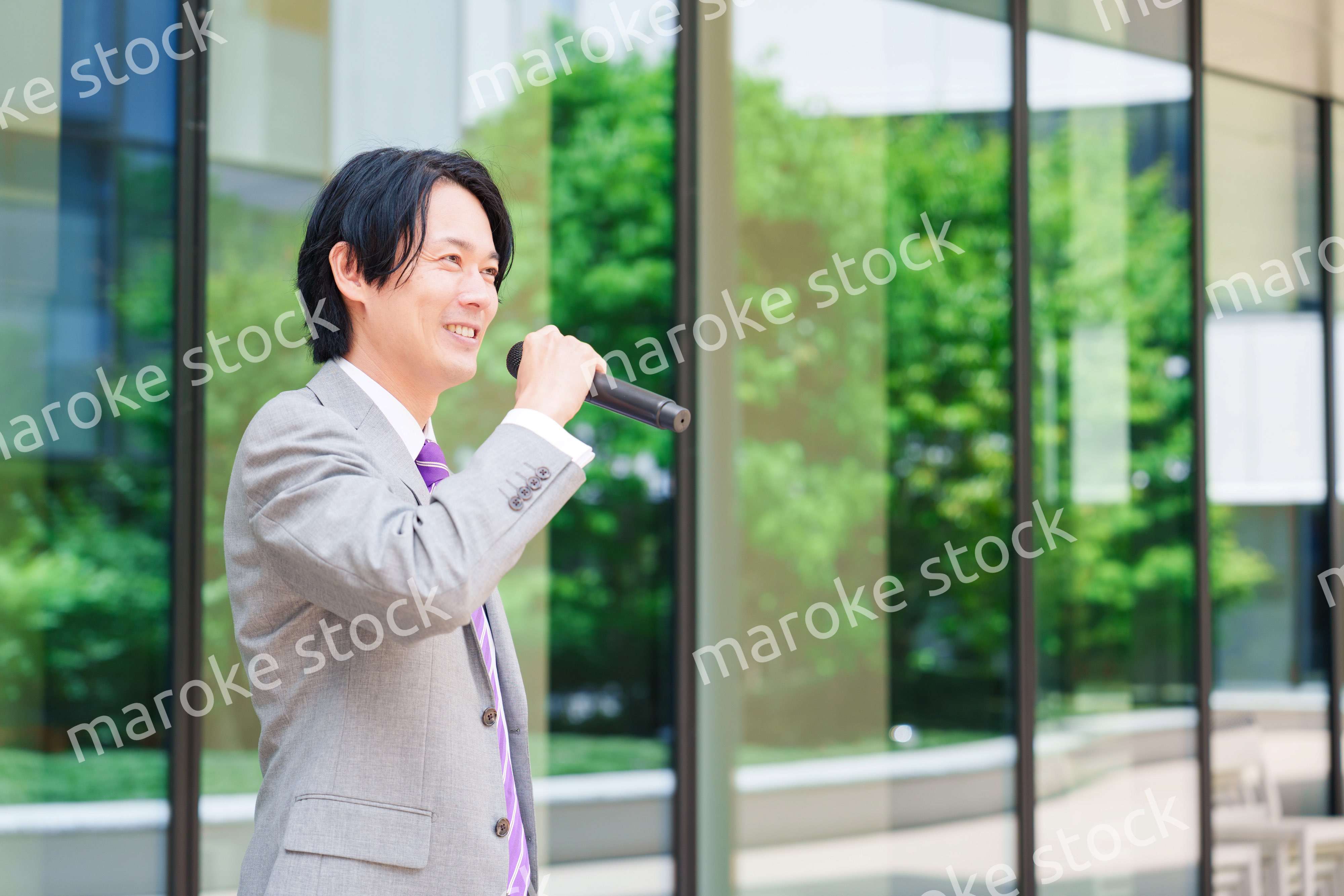 マイクを使って街なかで演説をするスーツを着た男性