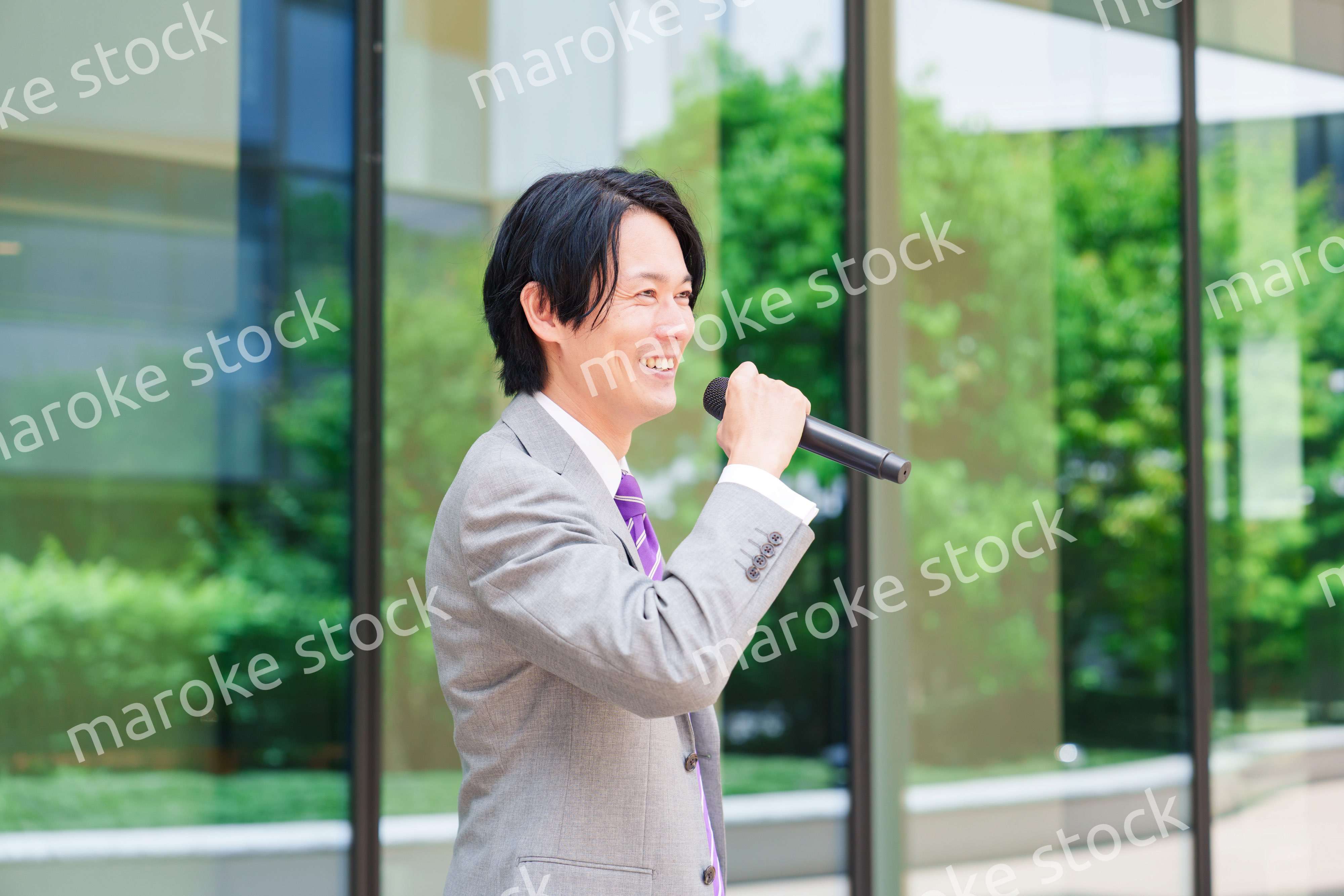 マイクを使って街なかで演説をするスーツを着た男性