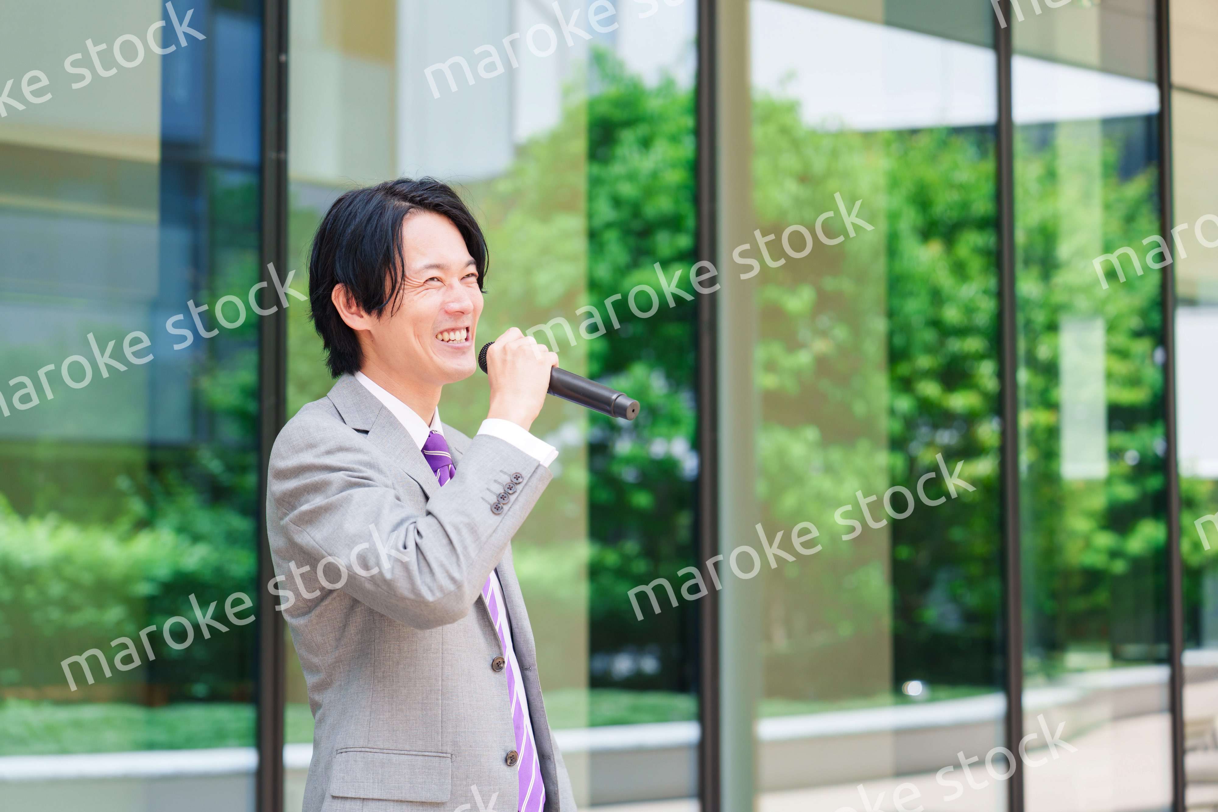 マイクを使って街なかで演説をするスーツを着た男性