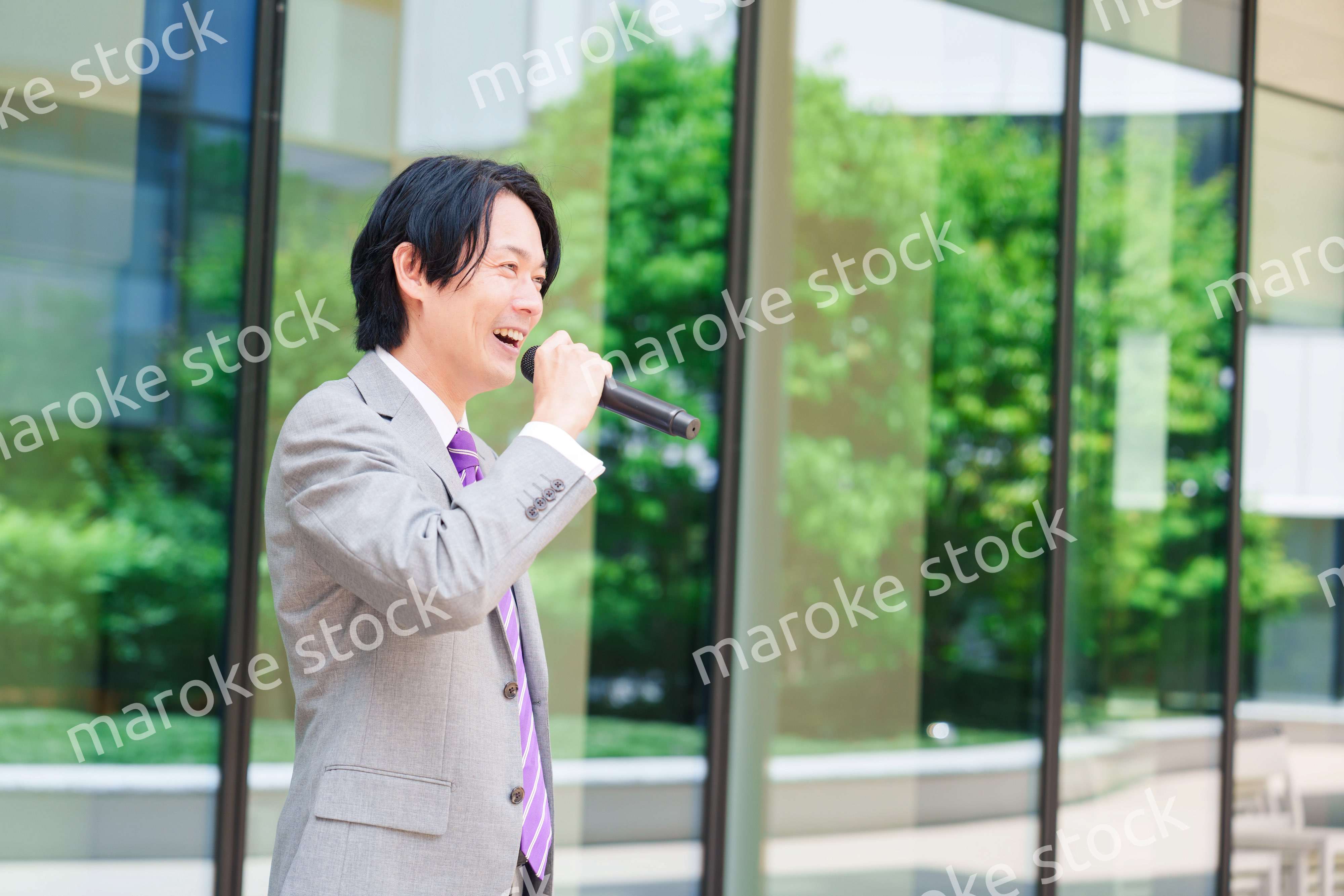 マイクを使って街なかで演説をするスーツを着た男性