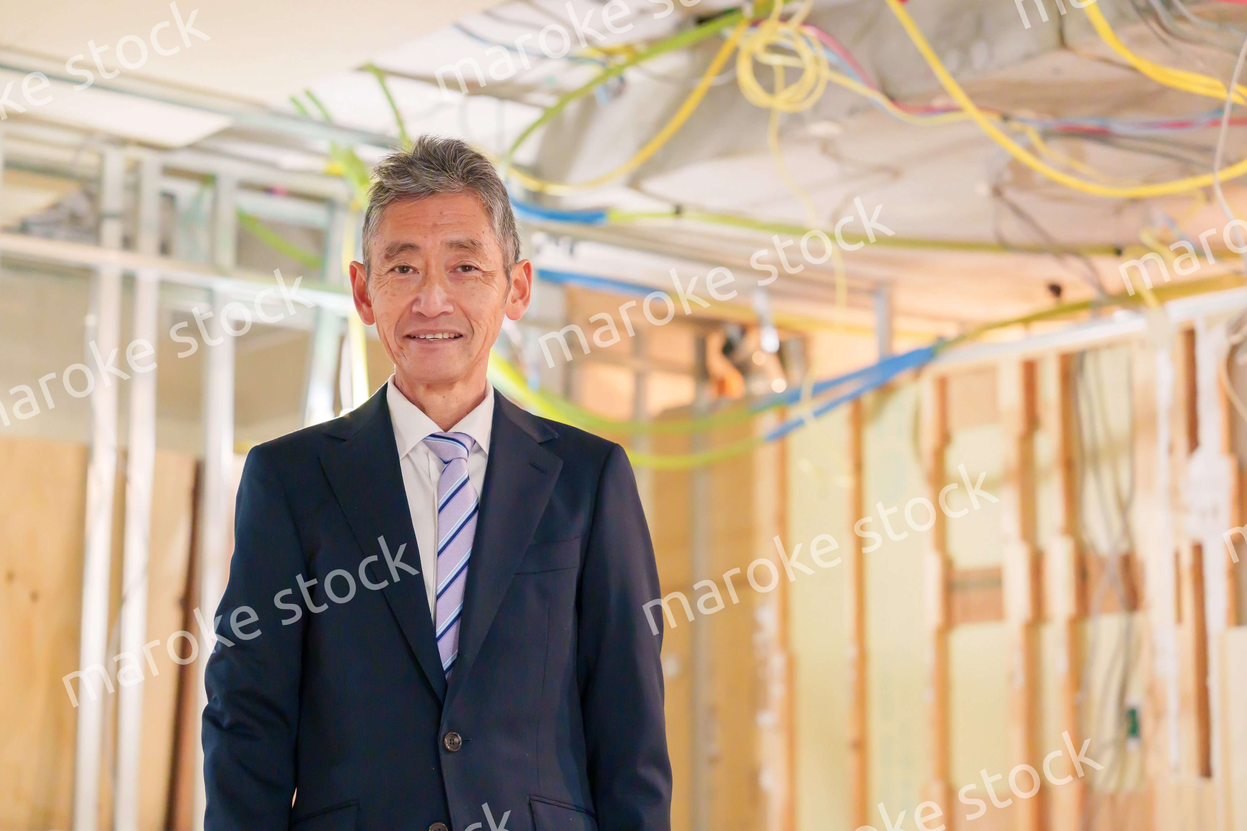 スーツ姿で現場に立つ工務店の男性経営者