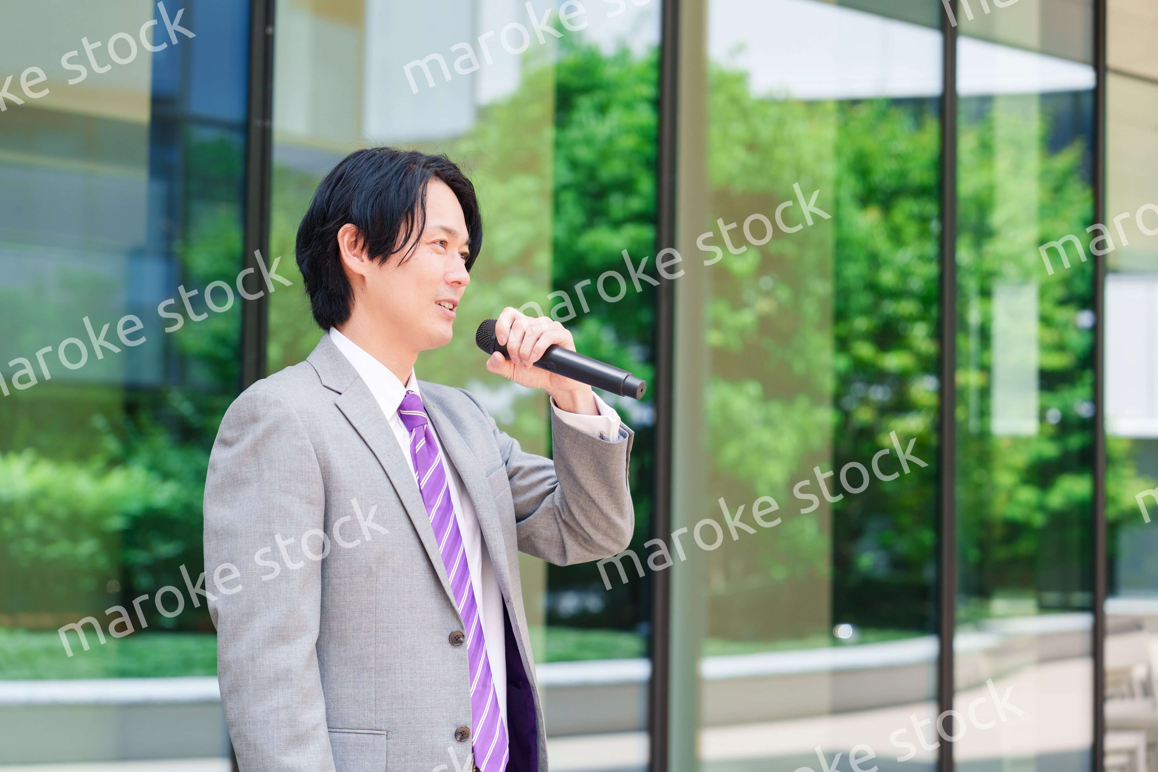 マイクを使って街なかで演説をするスーツを着た男性
