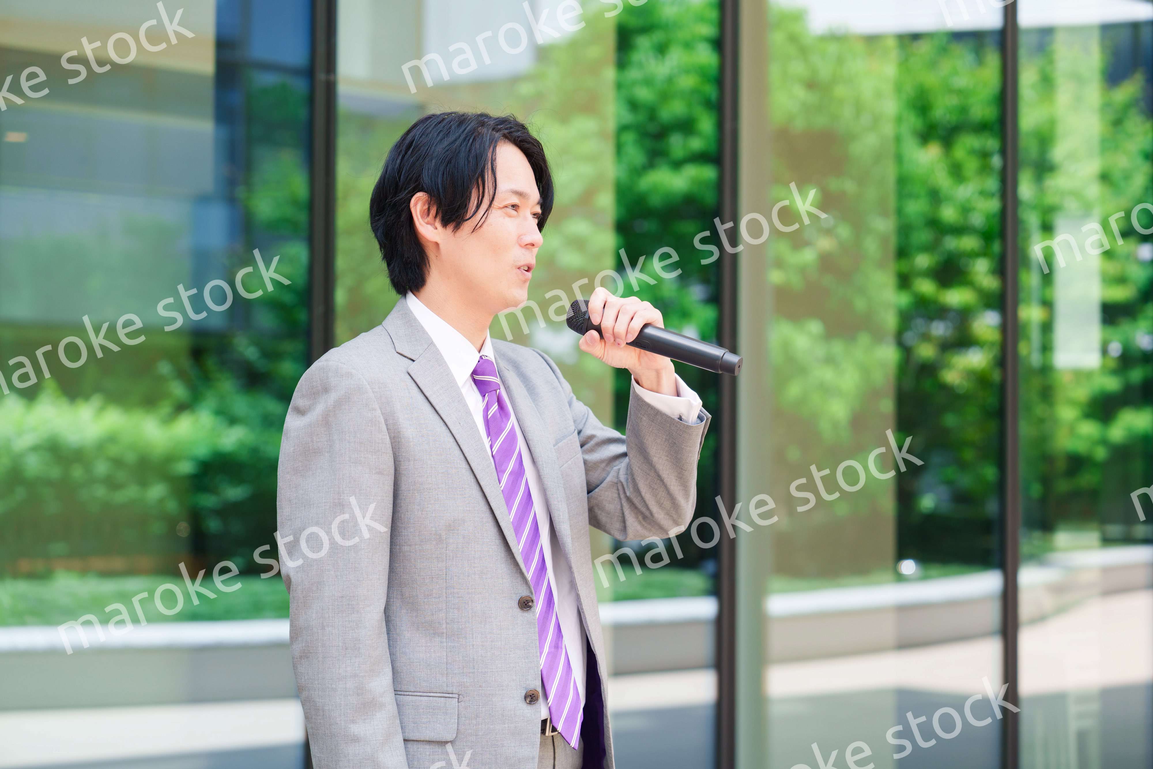 マイクを使って街なかで演説をするスーツを着た男性