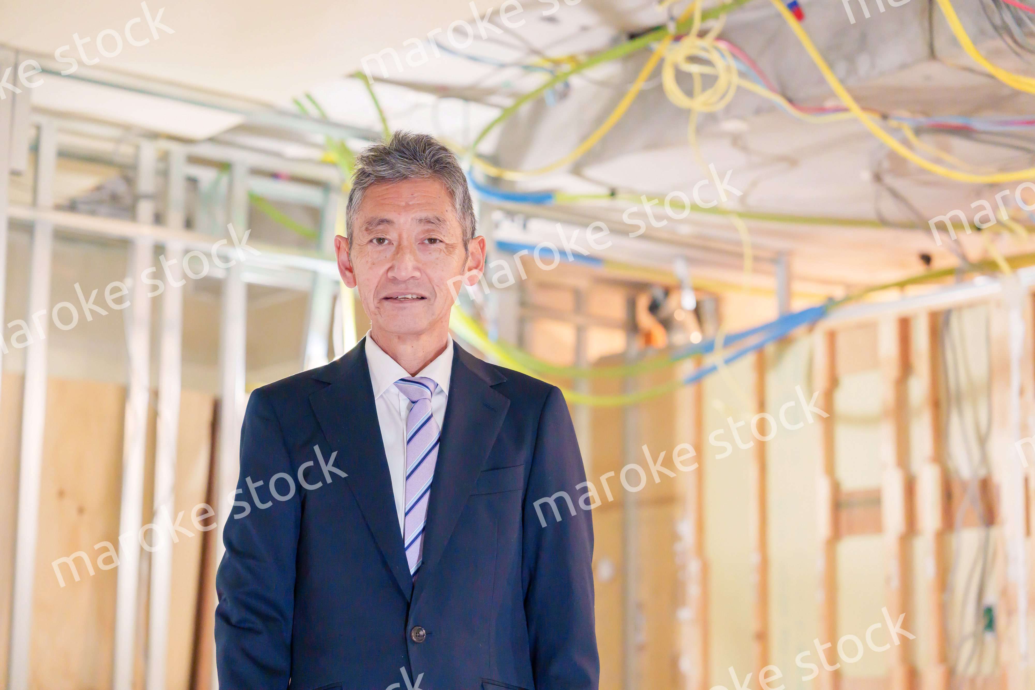 スーツ姿で現場に立つ工務店の男性経営者