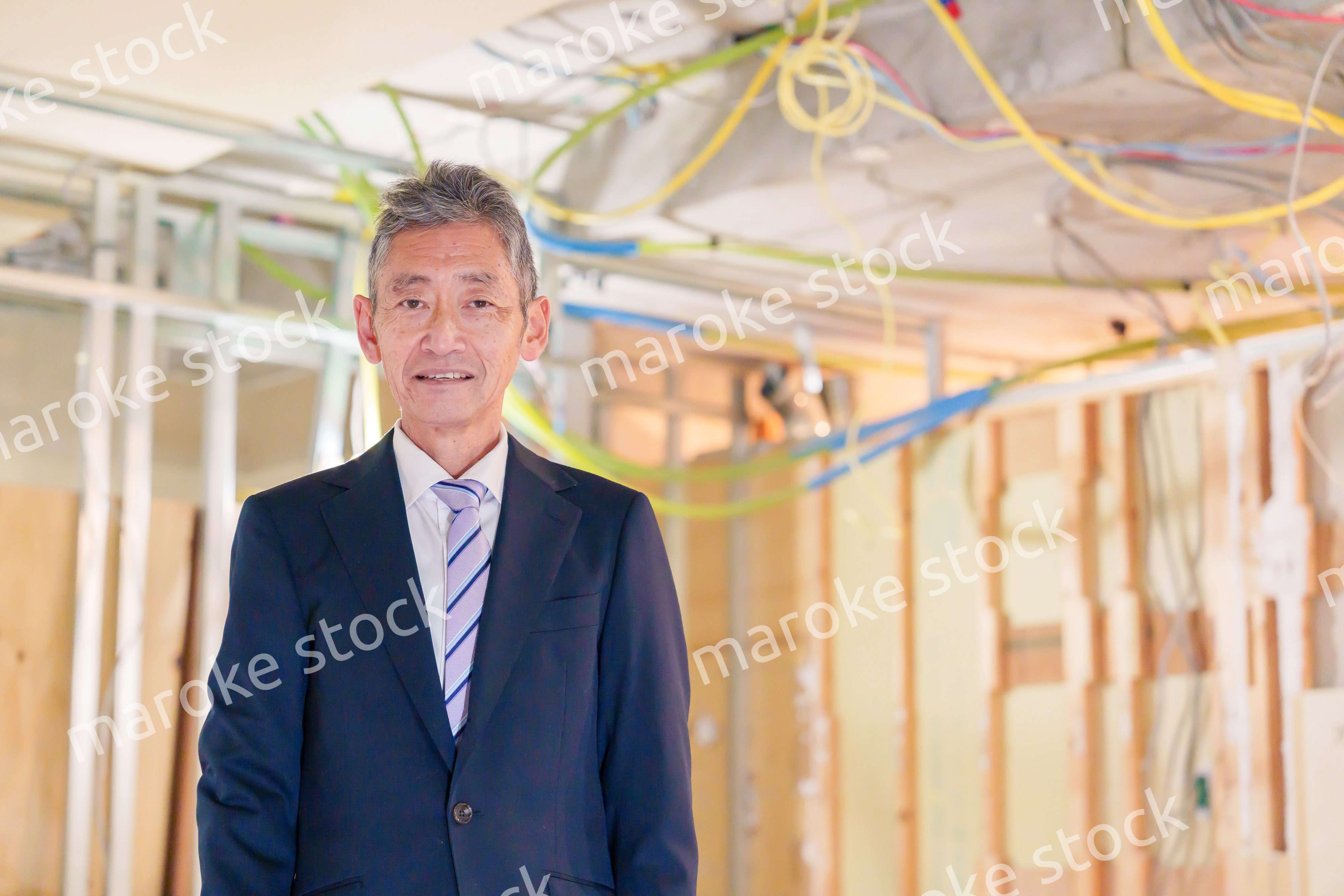 スーツ姿で現場に立つ工務店の男性経営者
