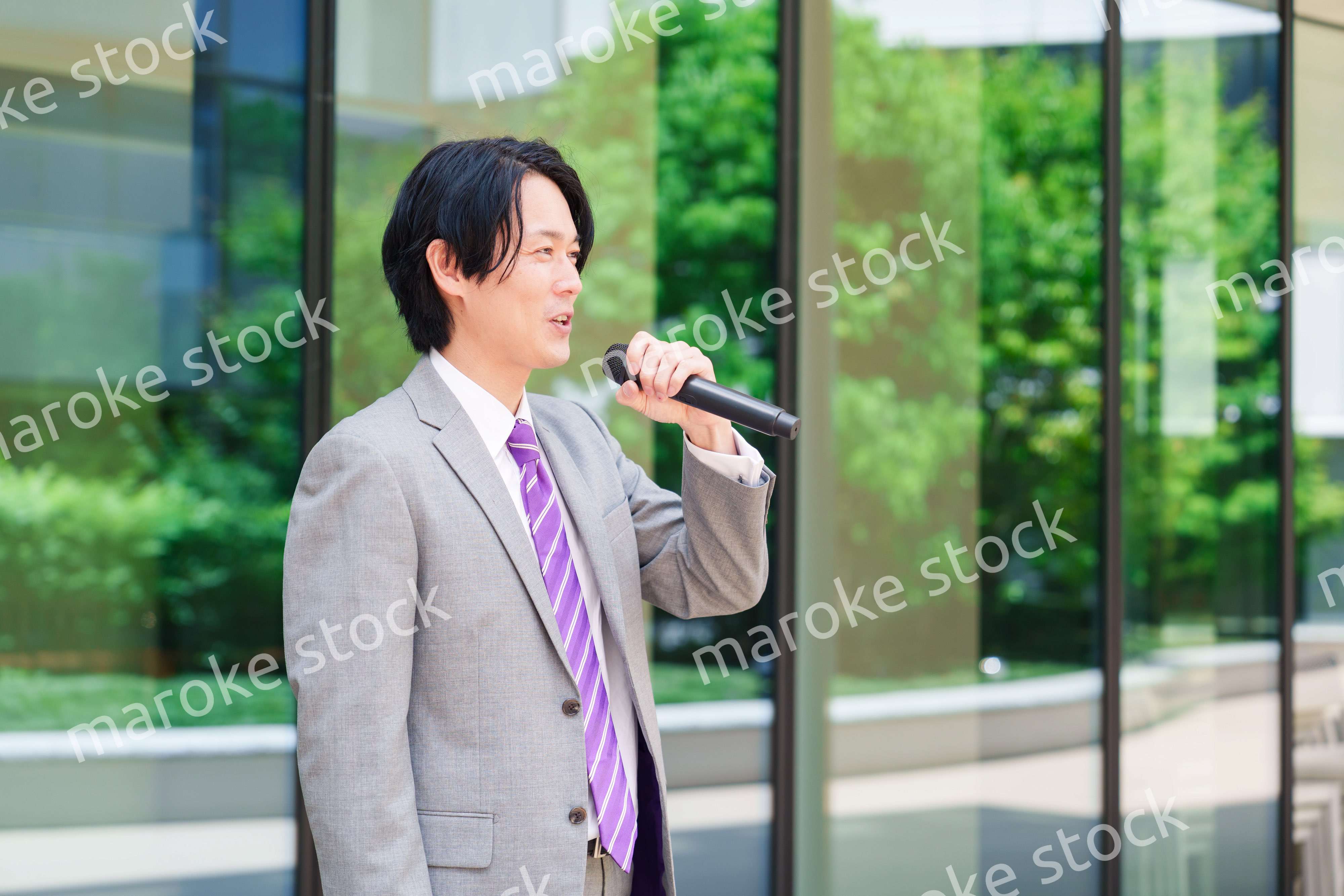 マイクを使って街なかで演説をするスーツを着た男性