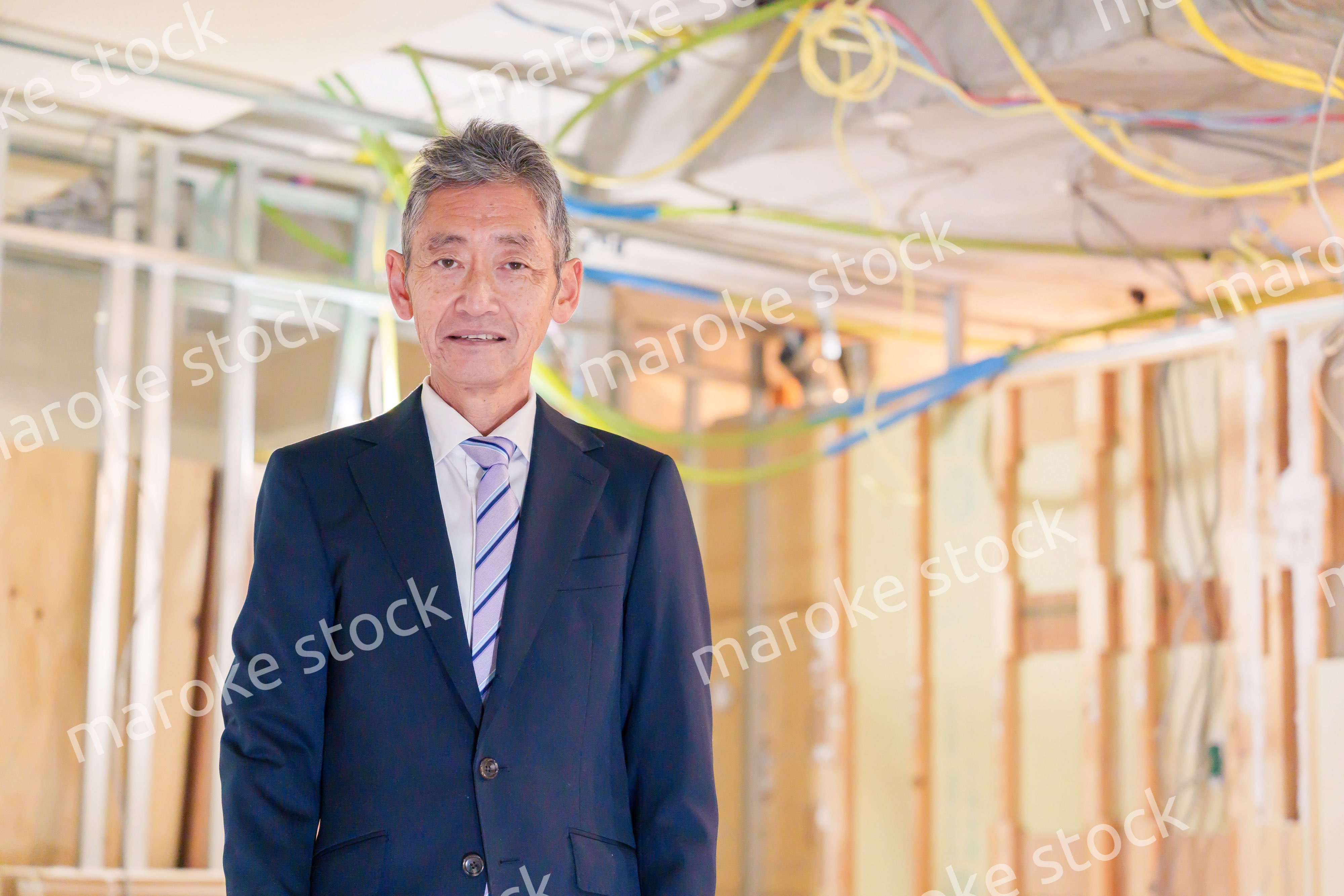 スーツ姿で現場に立つ工務店の男性経営者