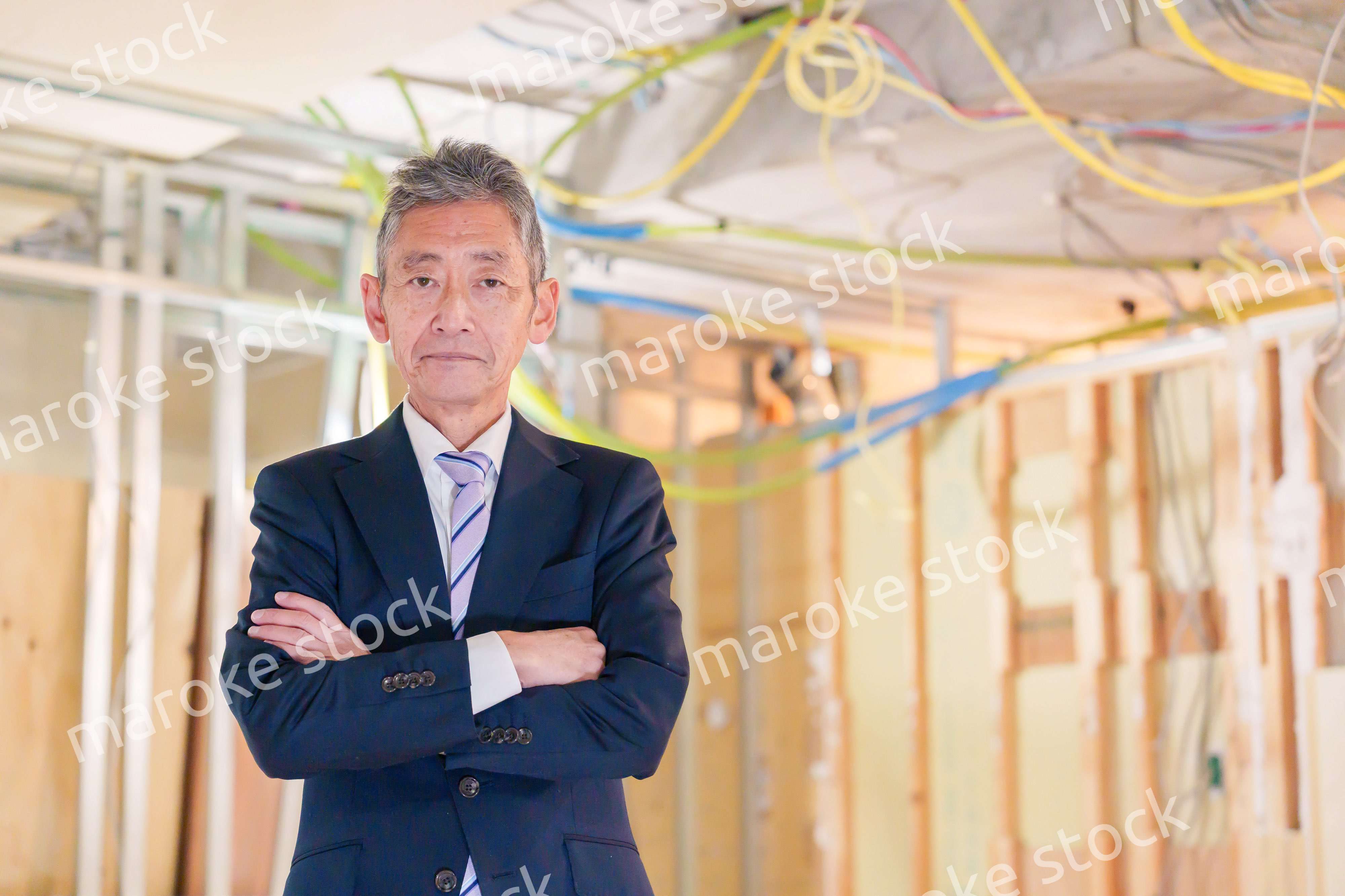 スーツ姿で現場に立つ工務店の男性経営者