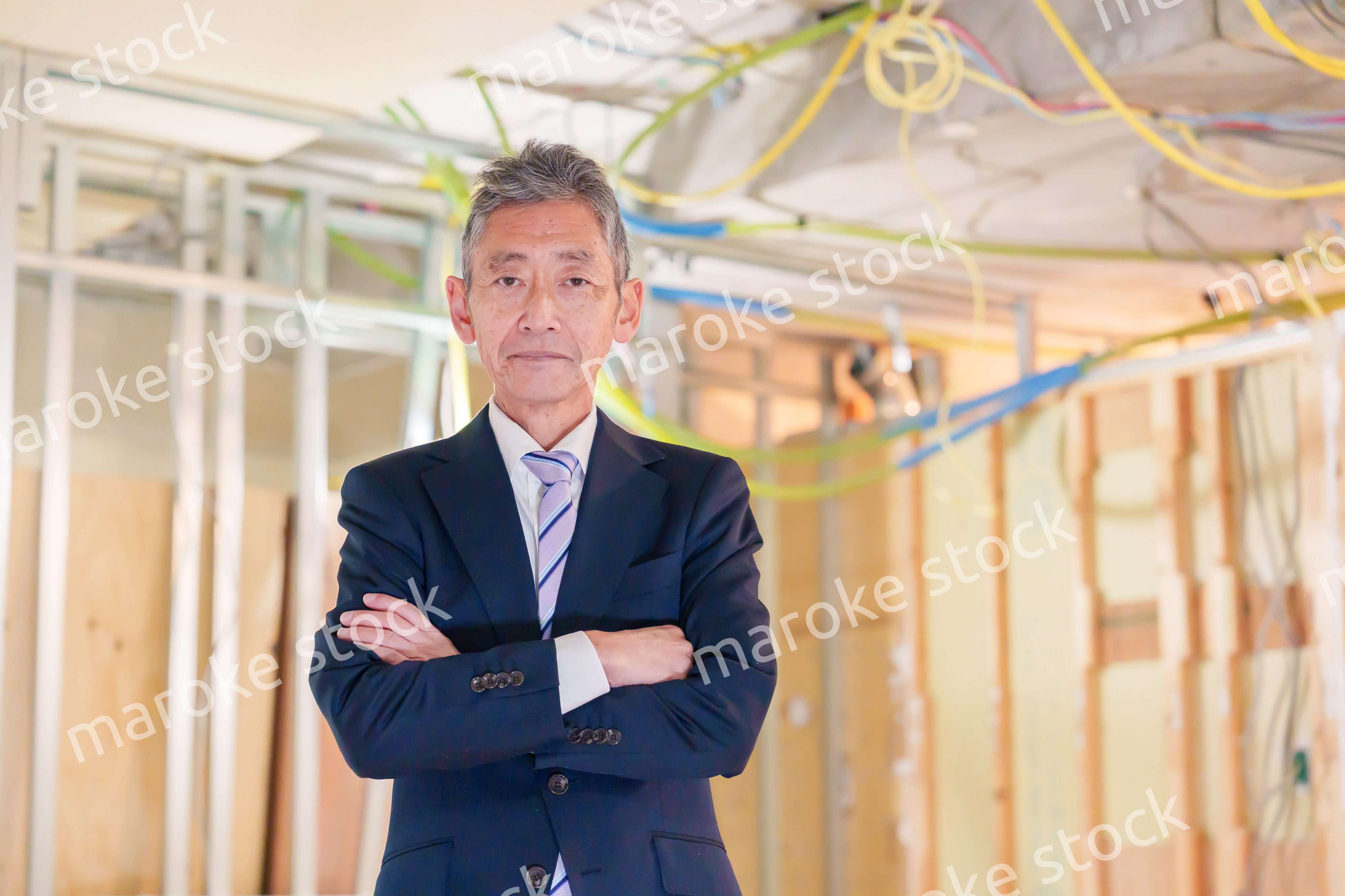 スーツ姿で現場に立つ工務店の男性経営者