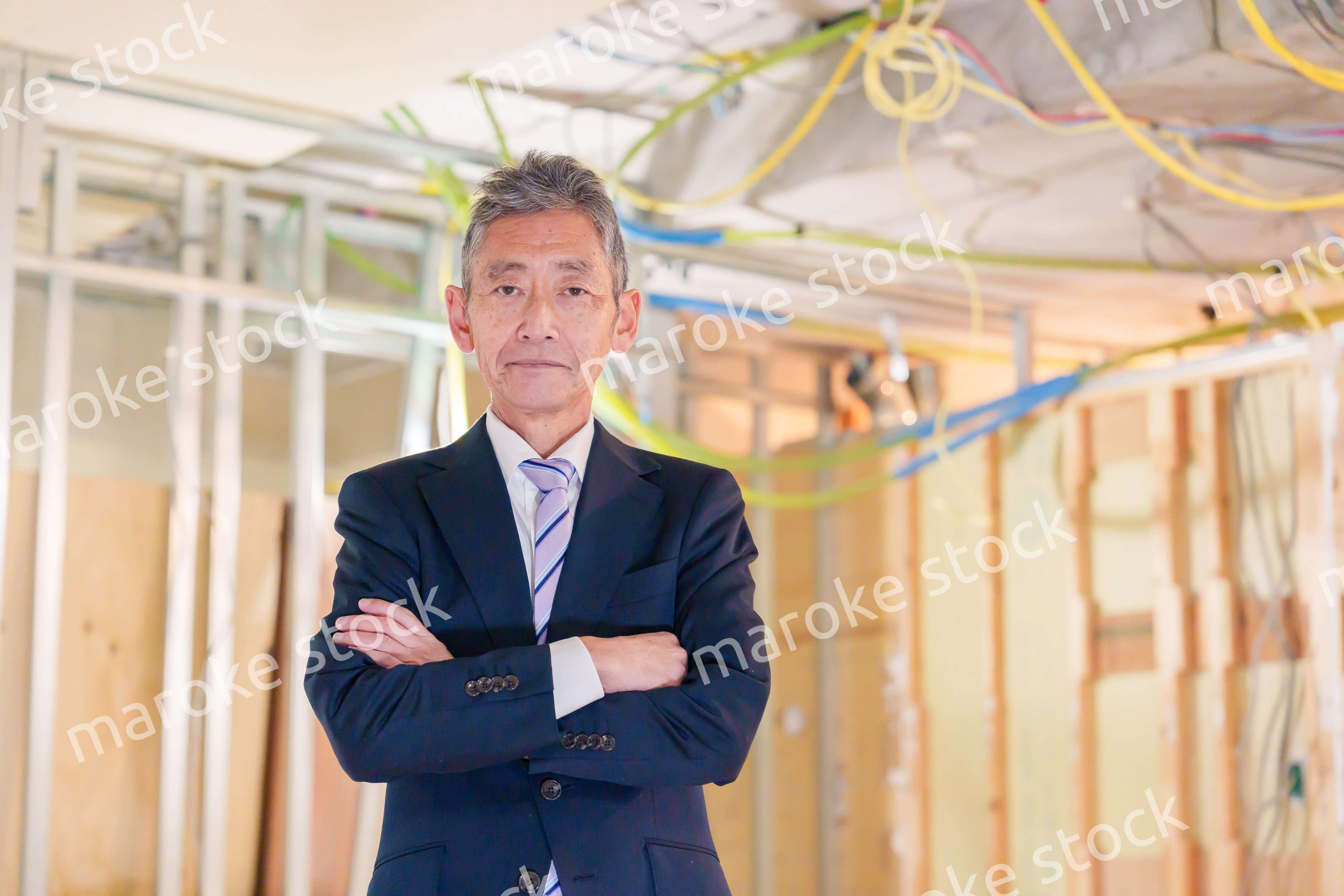 スーツ姿で現場に立つ工務店の男性経営者