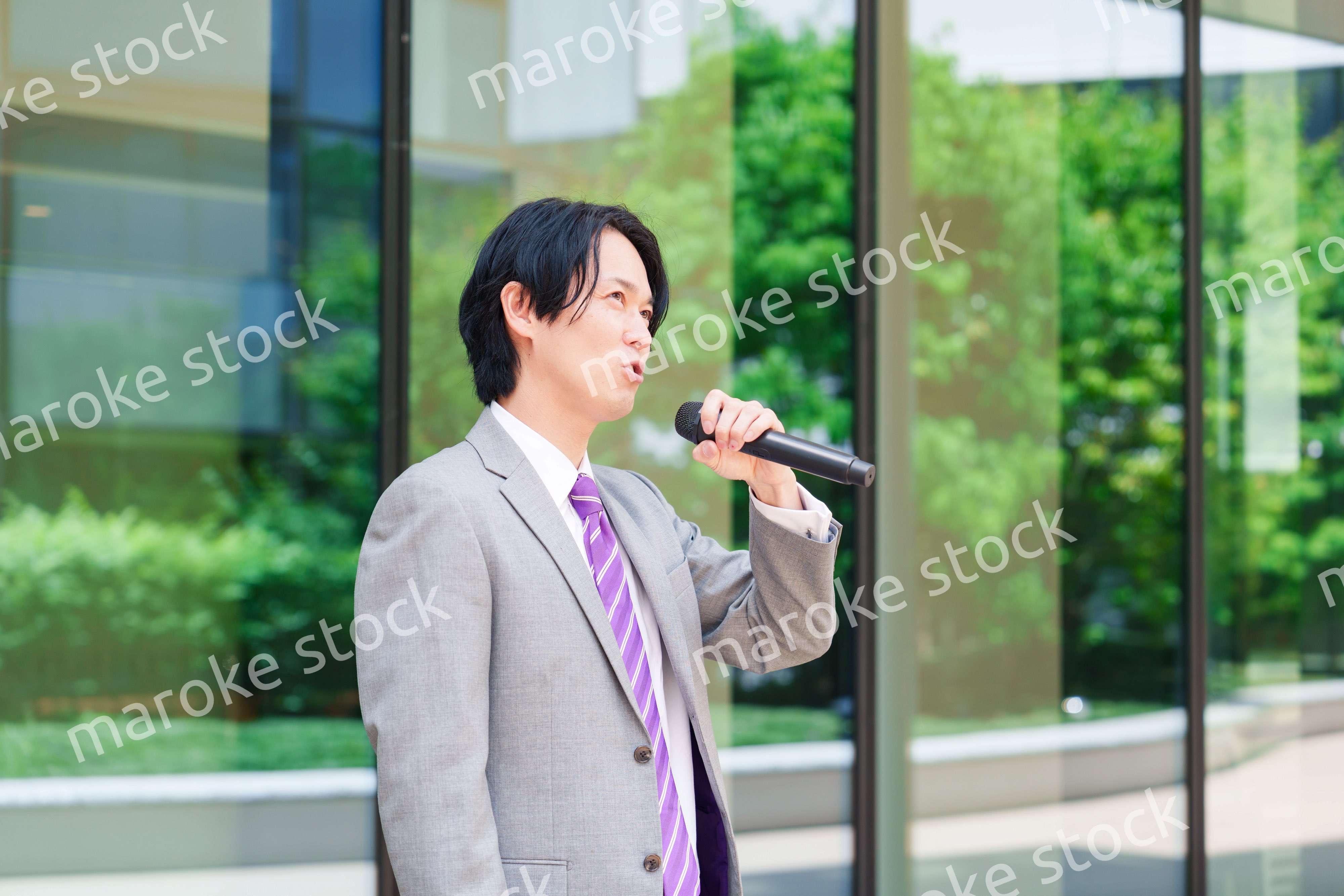 マイクを使って街なかで演説をするスーツを着た男性