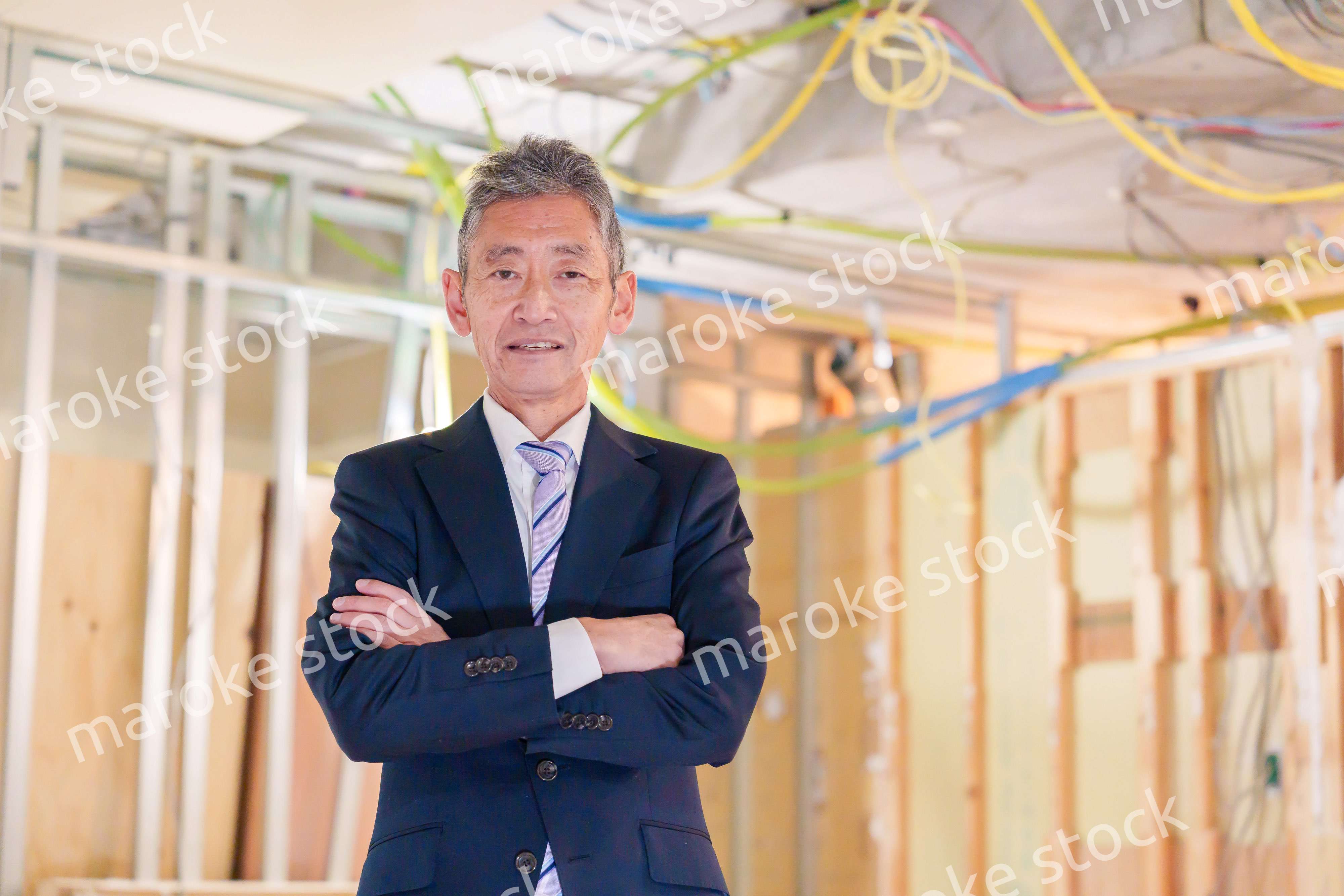 スーツ姿で現場に立つ工務店の男性経営者