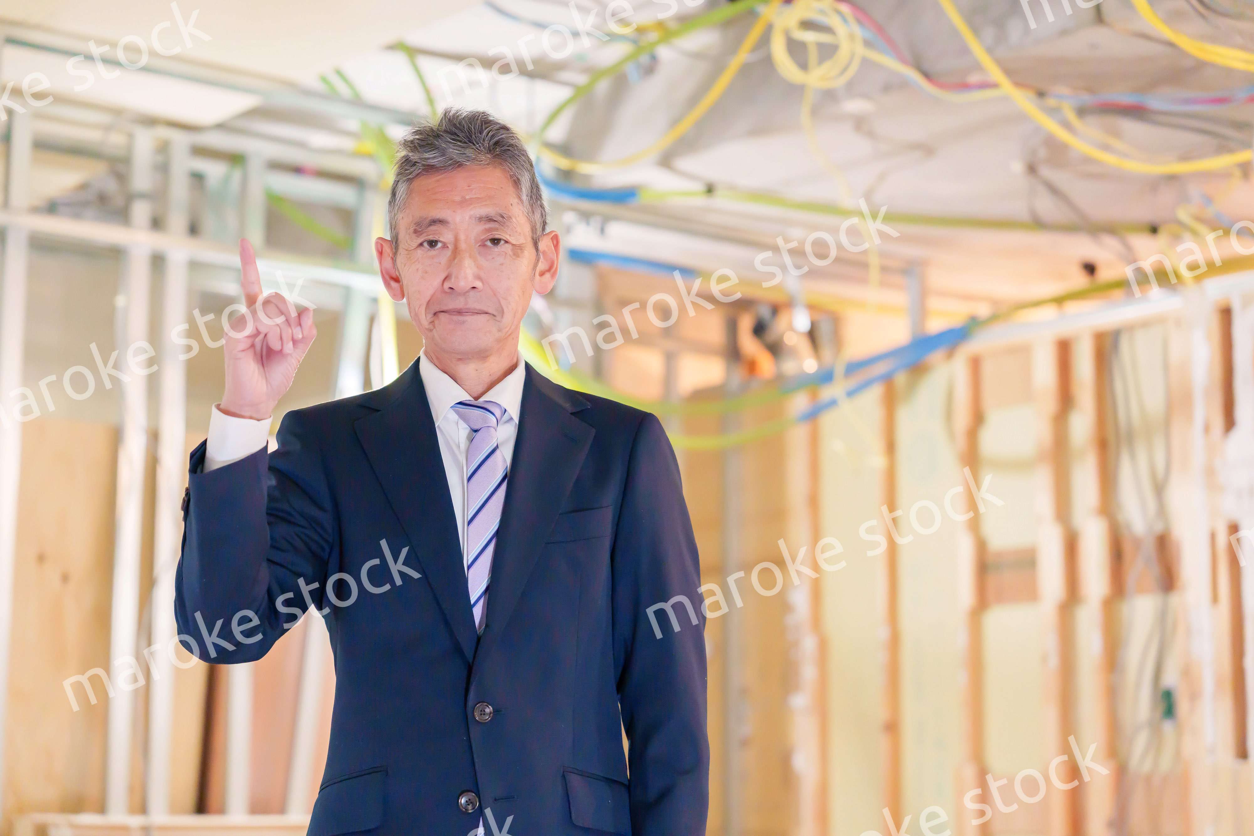 スーツ姿で現場に立つ工務店の男性経営者