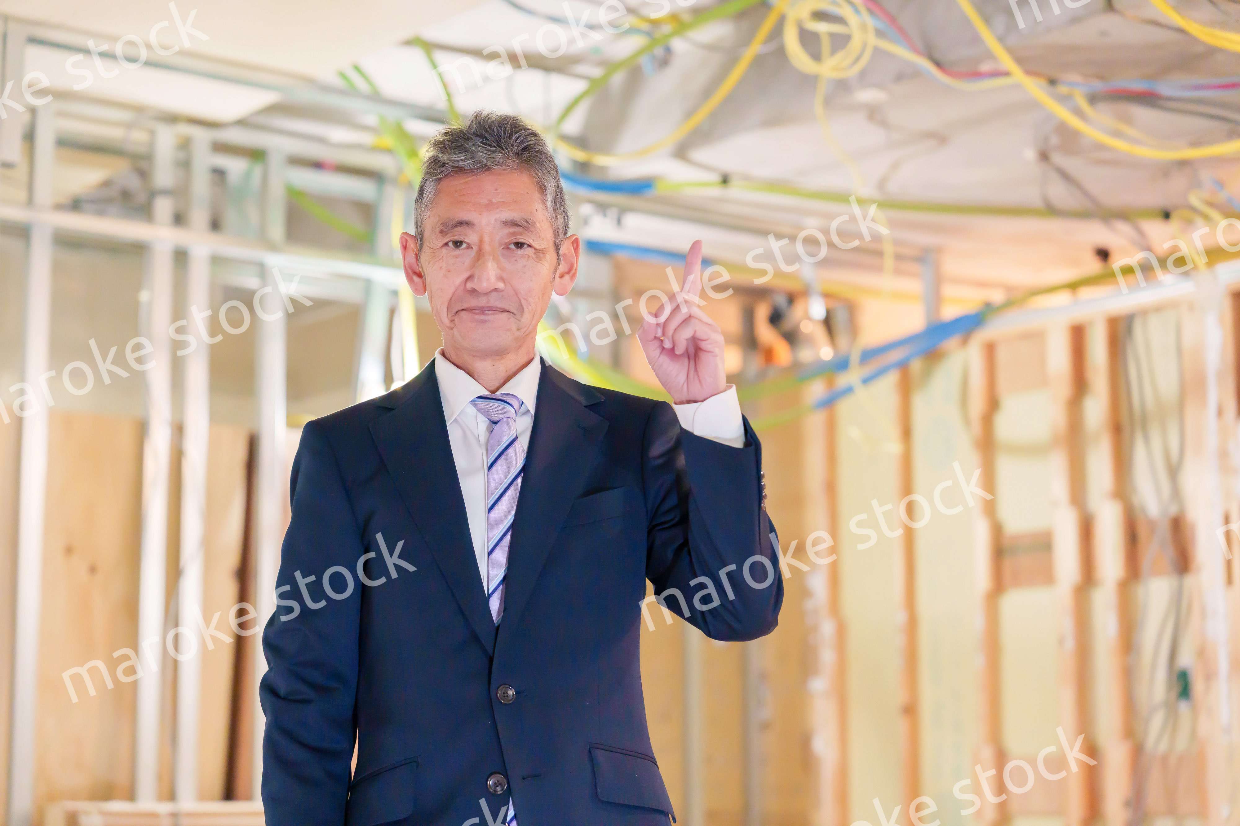 スーツ姿で現場に立つ工務店の男性経営者