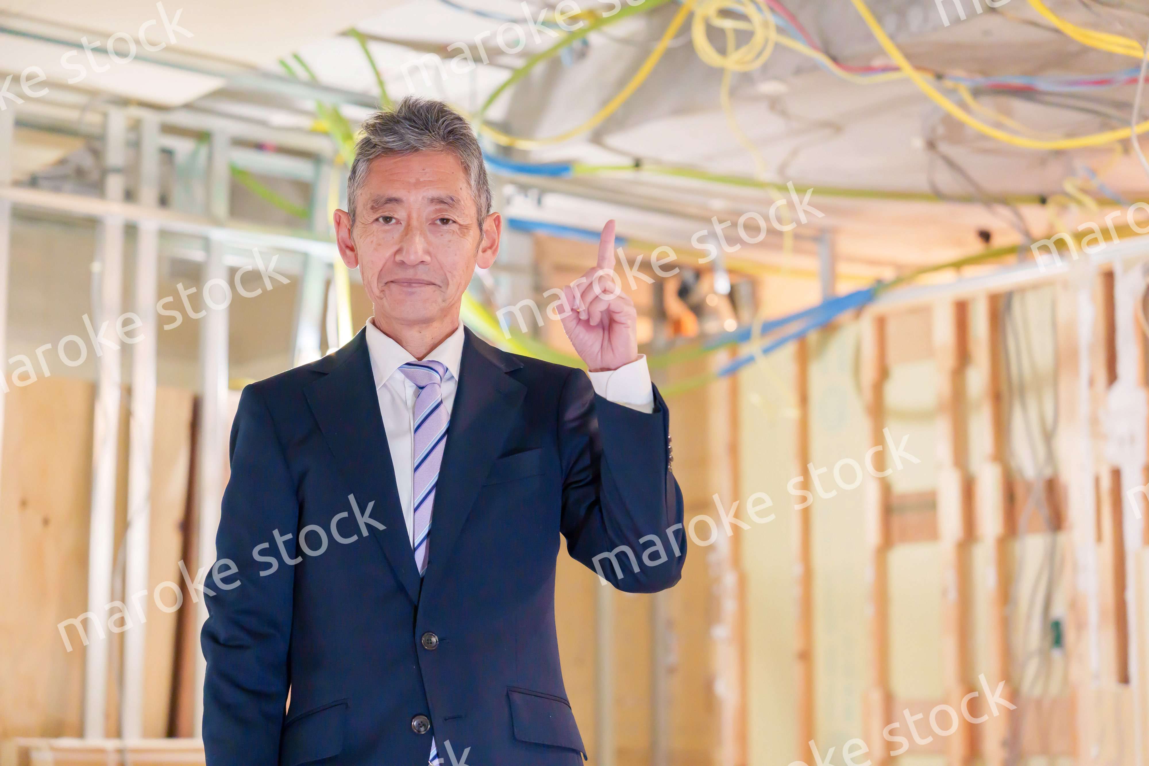 スーツ姿で現場に立つ工務店の男性経営者