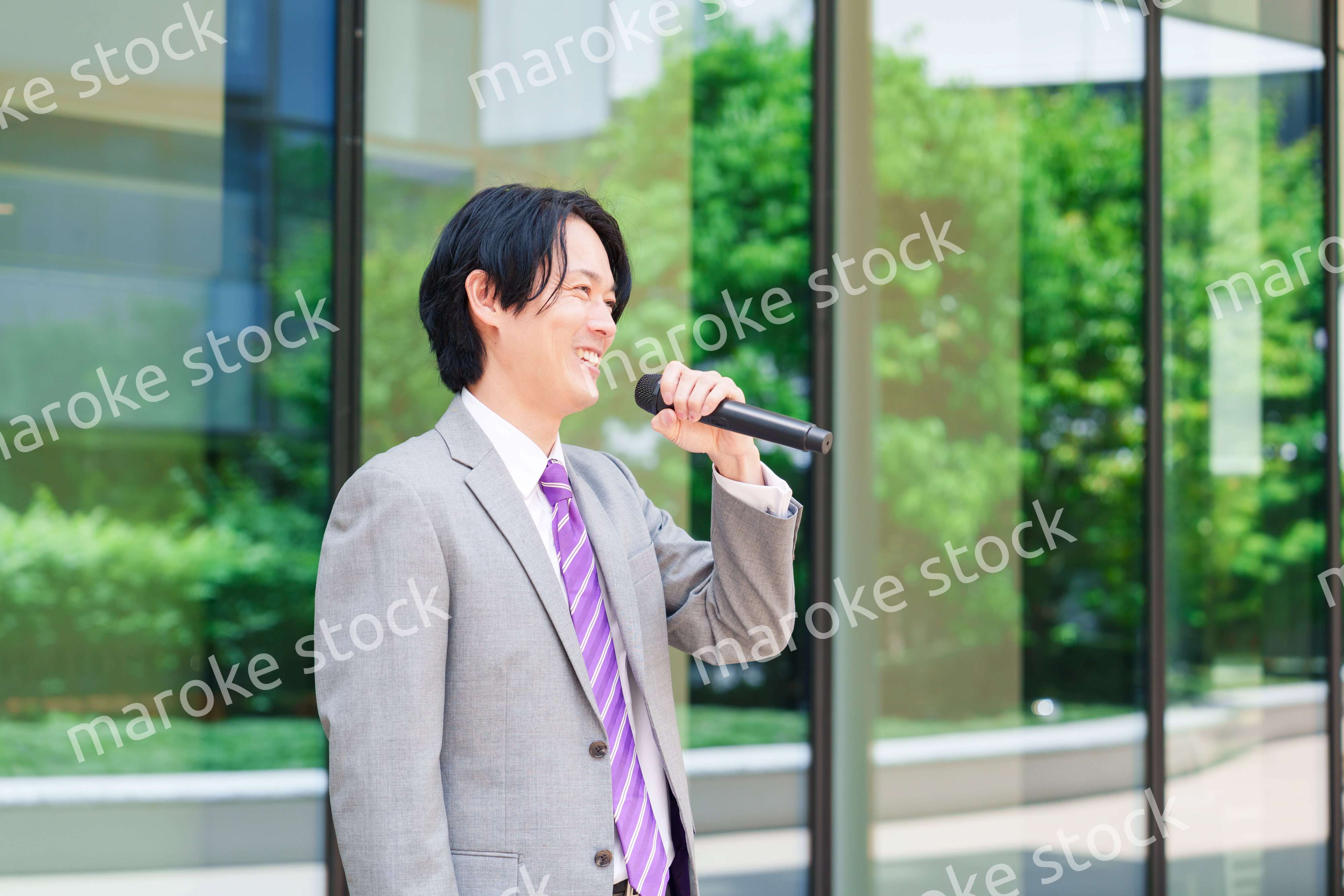 マイクを使って街なかで演説をするスーツを着た男性