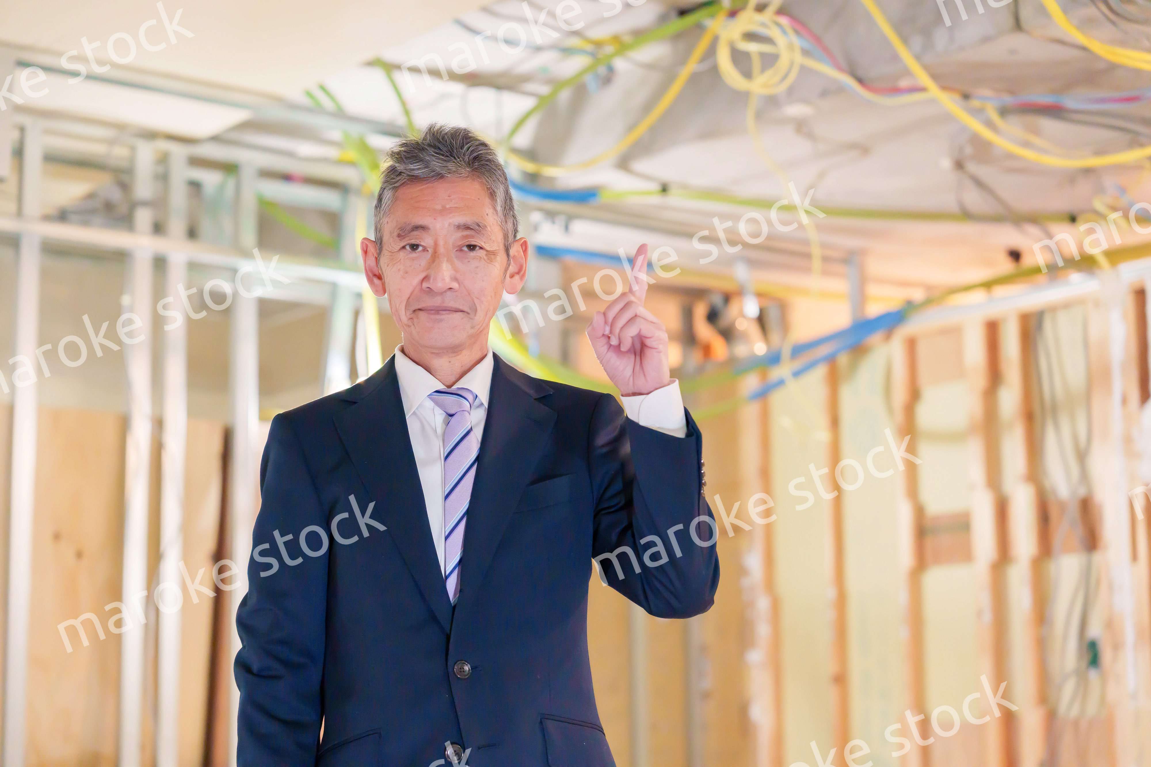 スーツ姿で現場に立つ工務店の男性経営者