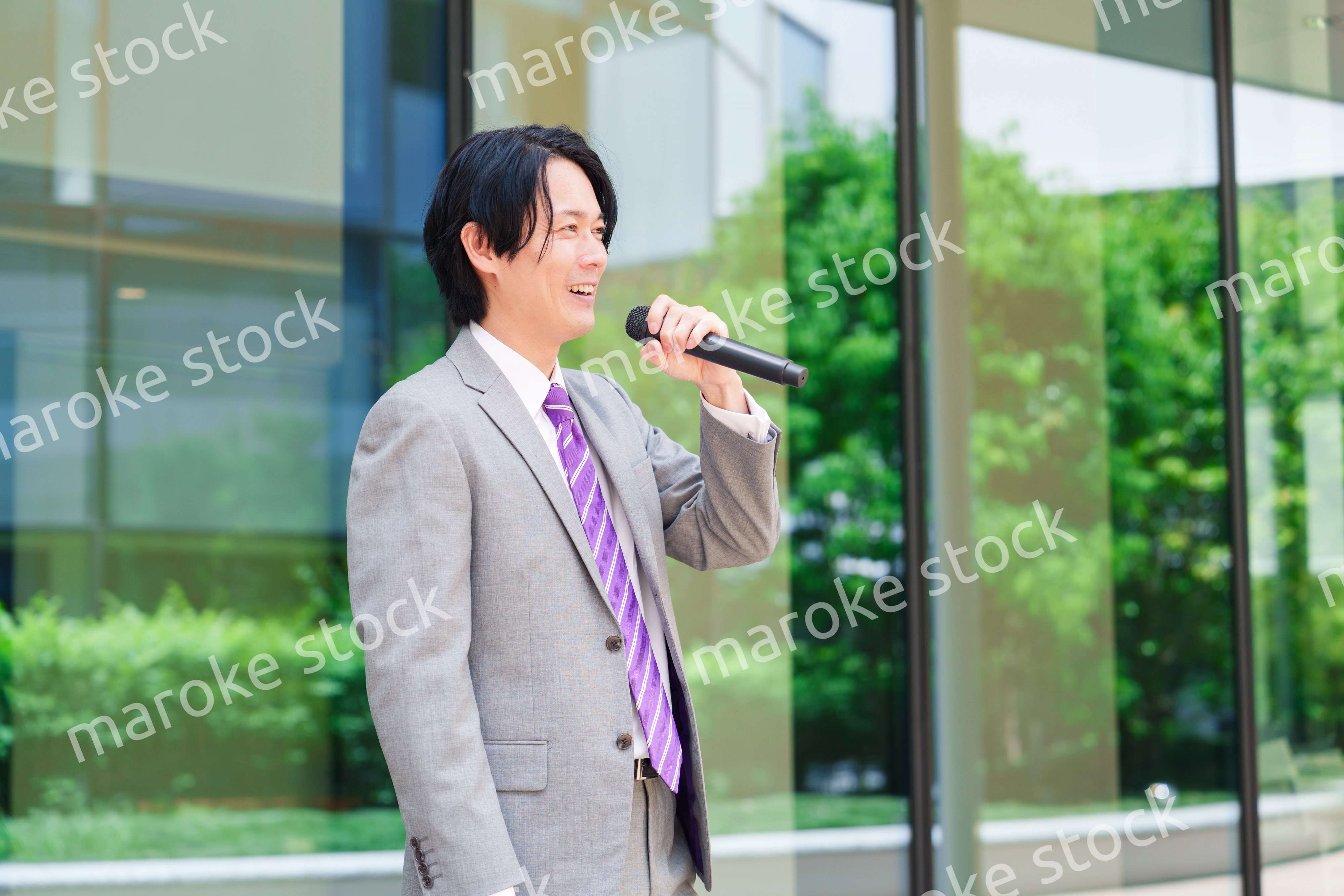 マイクを使って街なかで演説をするスーツを着た男性