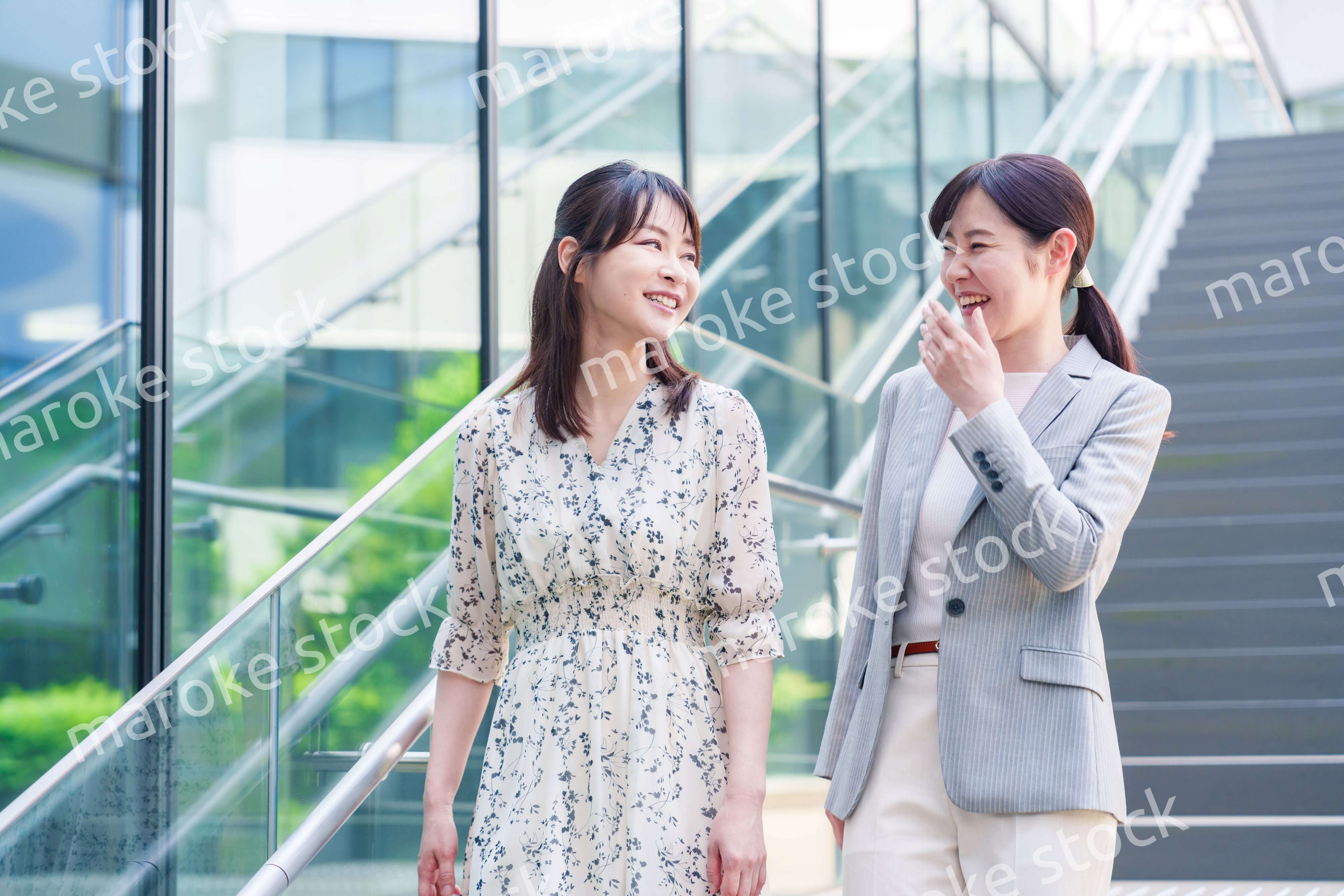 楽しく話しながらオフィスの中を歩く女性ビジネスパーソン