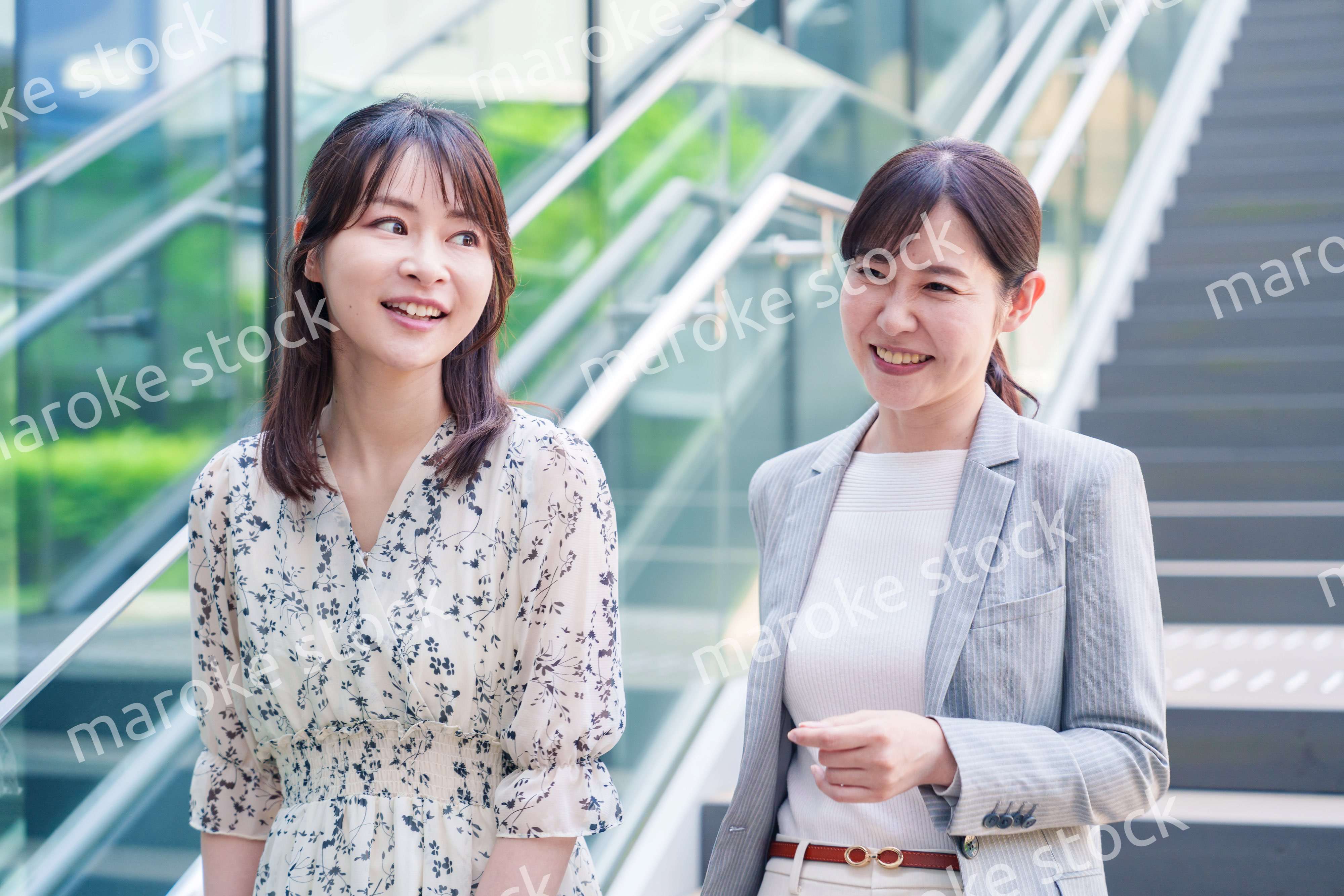 楽しく話しながらオフィスの中を歩く女性ビジネスパーソン