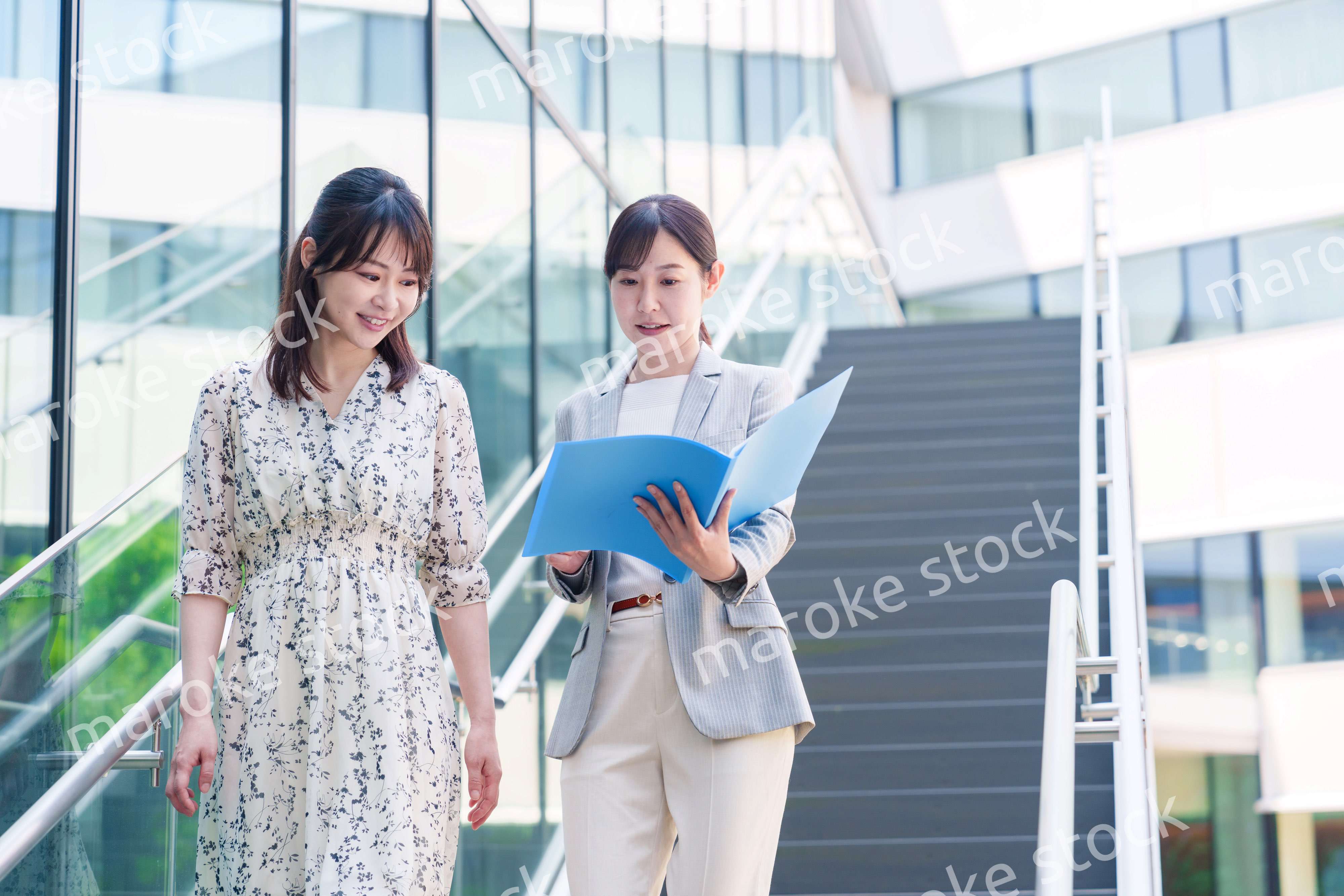 楽しく話しながらオフィスの中を歩く女性ビジネスパーソン