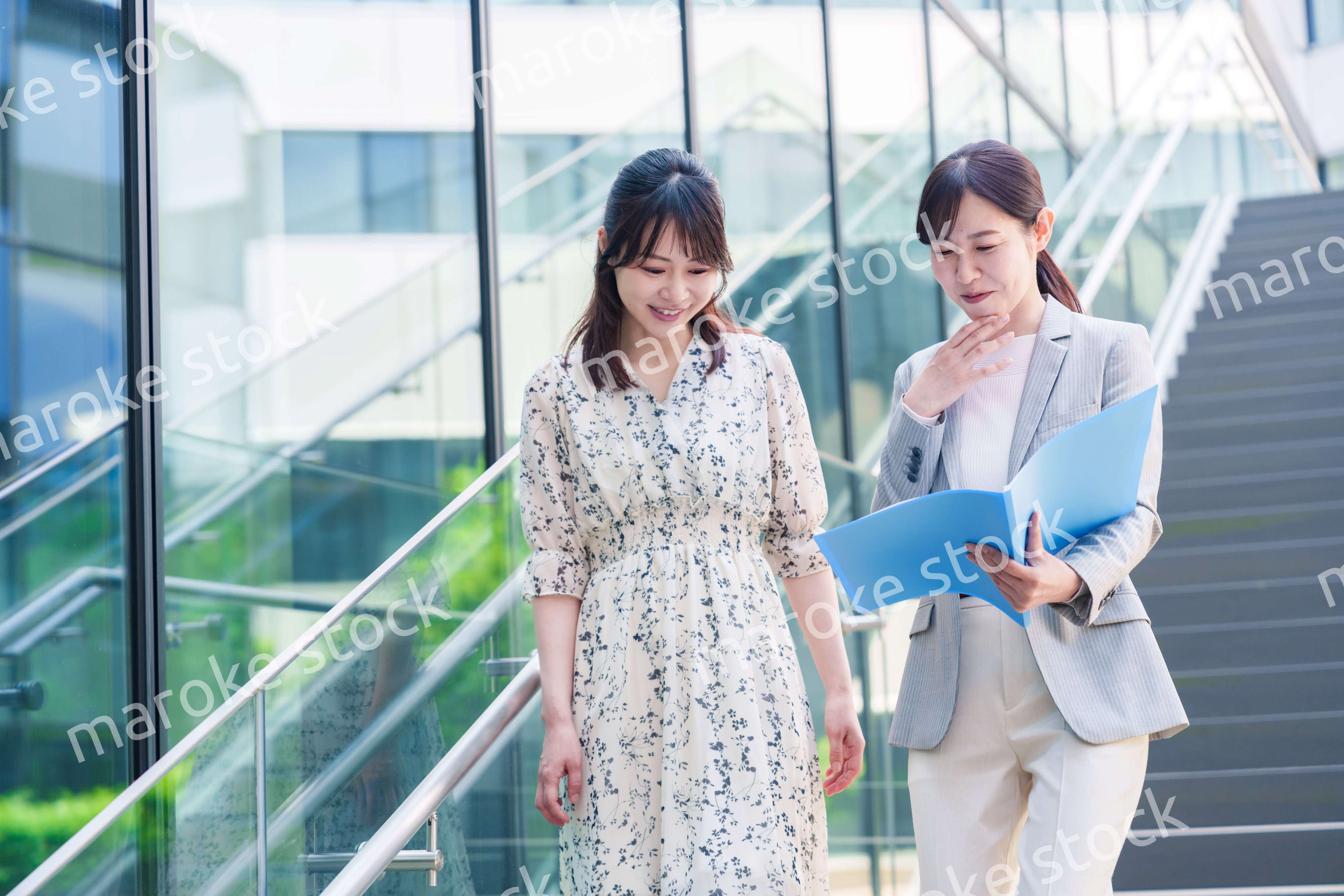 楽しく話しながらオフィスの中を歩く女性ビジネスパーソン