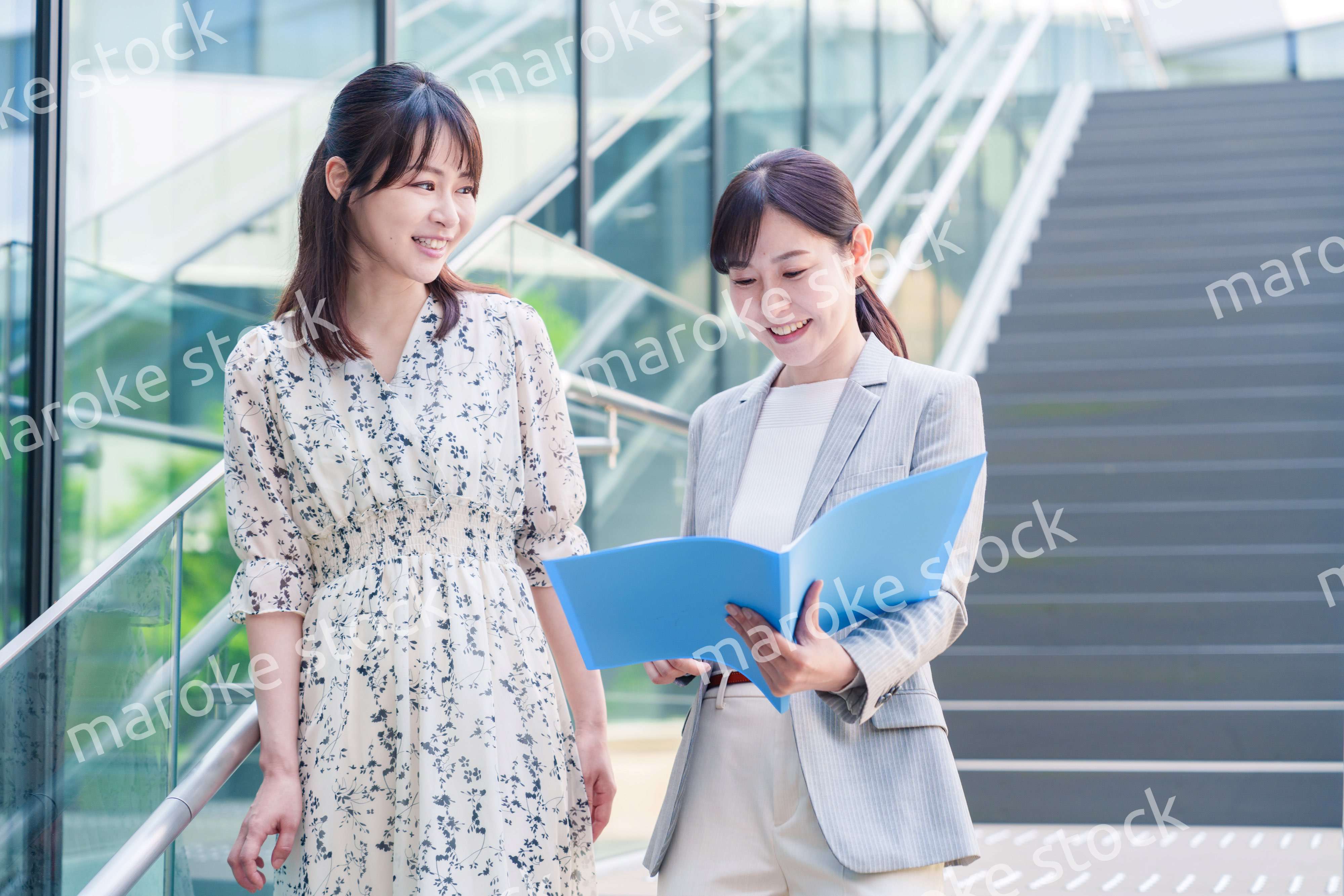 楽しく話しながらオフィスの中を歩く女性ビジネスパーソン